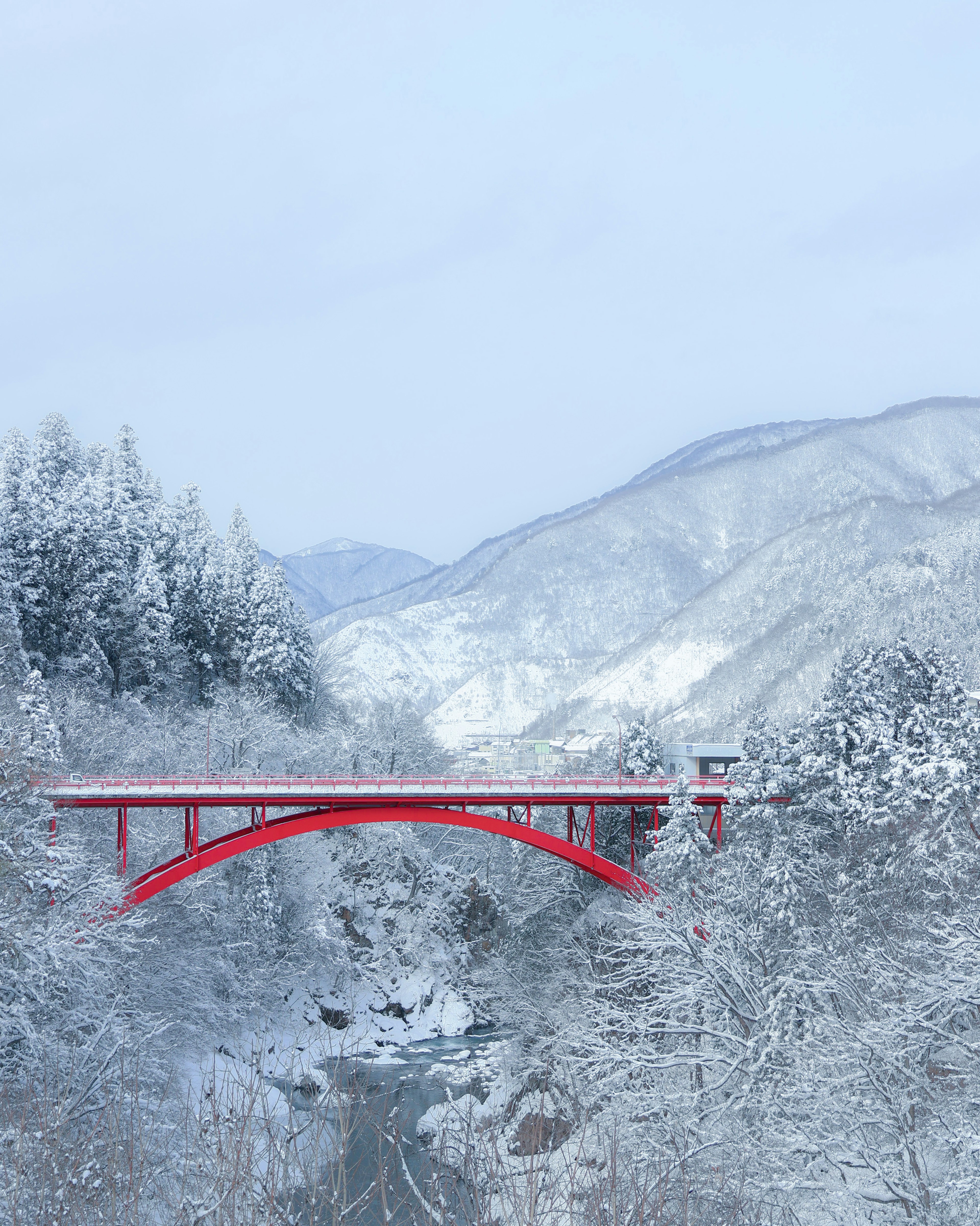 Paesaggio innevato con un ponte rosso e montagne