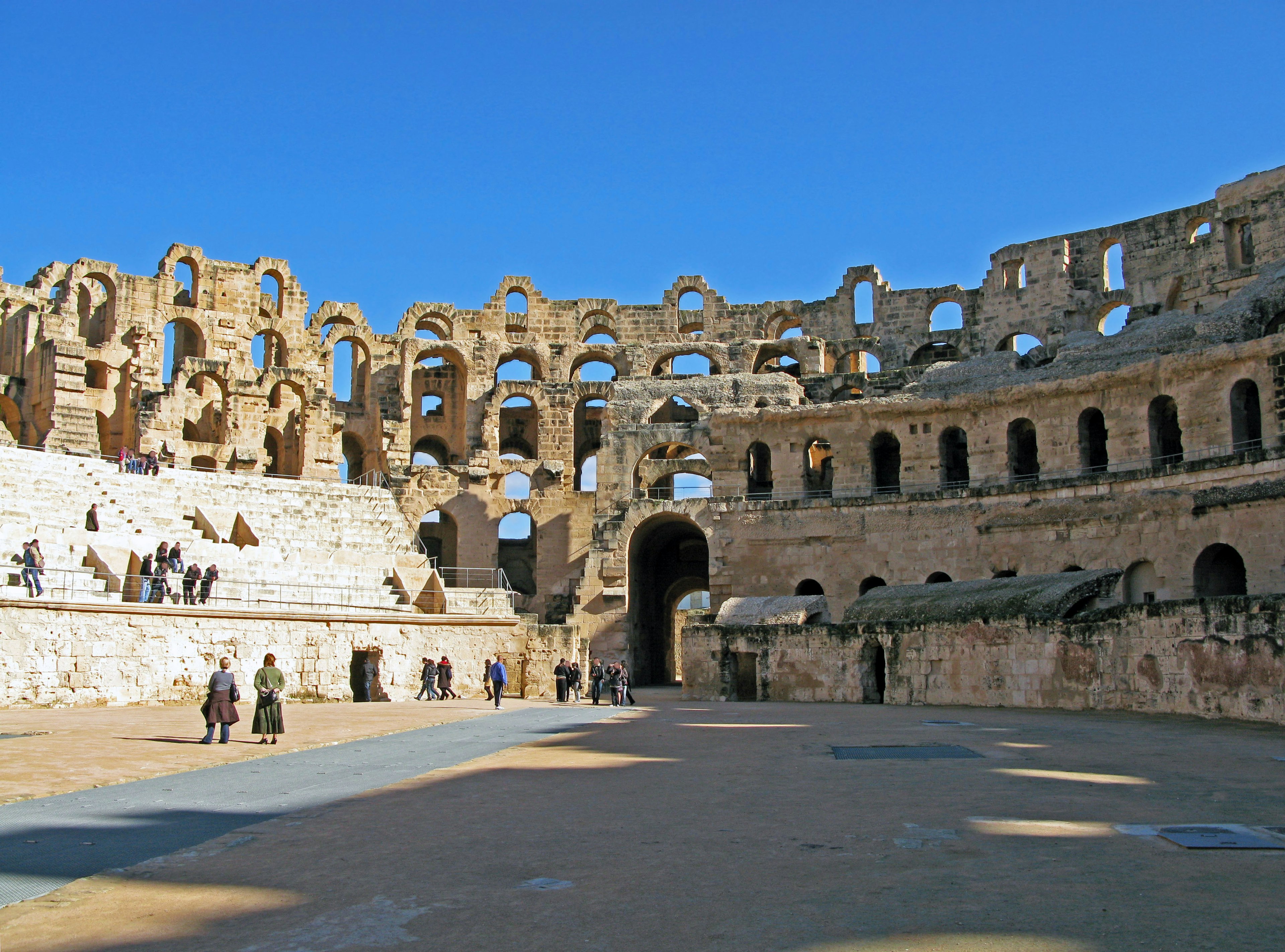 Interior view of an ancient amphitheater with visible seating under a blue sky