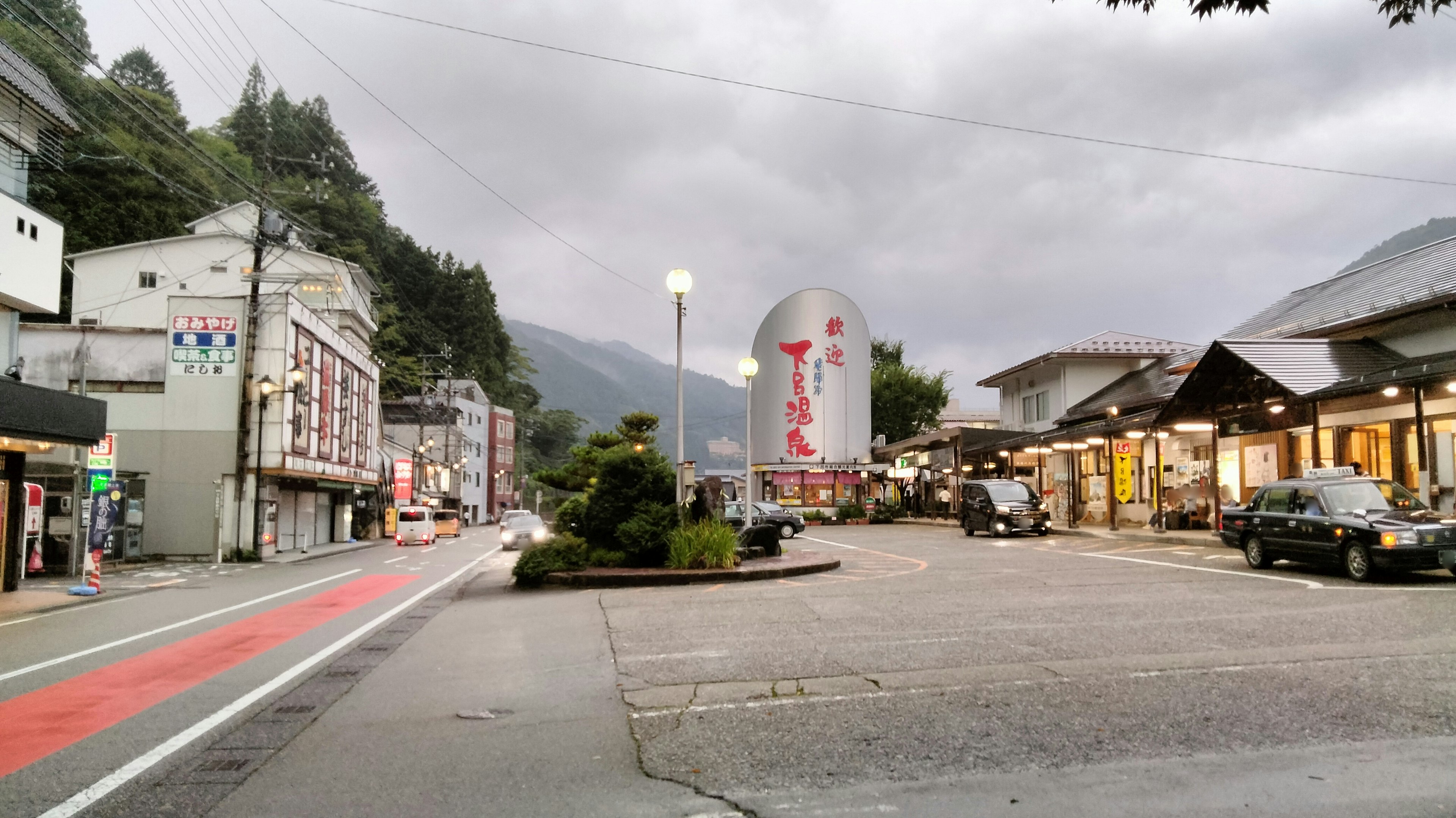 Scena di strada in una città di montagna con un grande cartello sotto un cielo nuvoloso