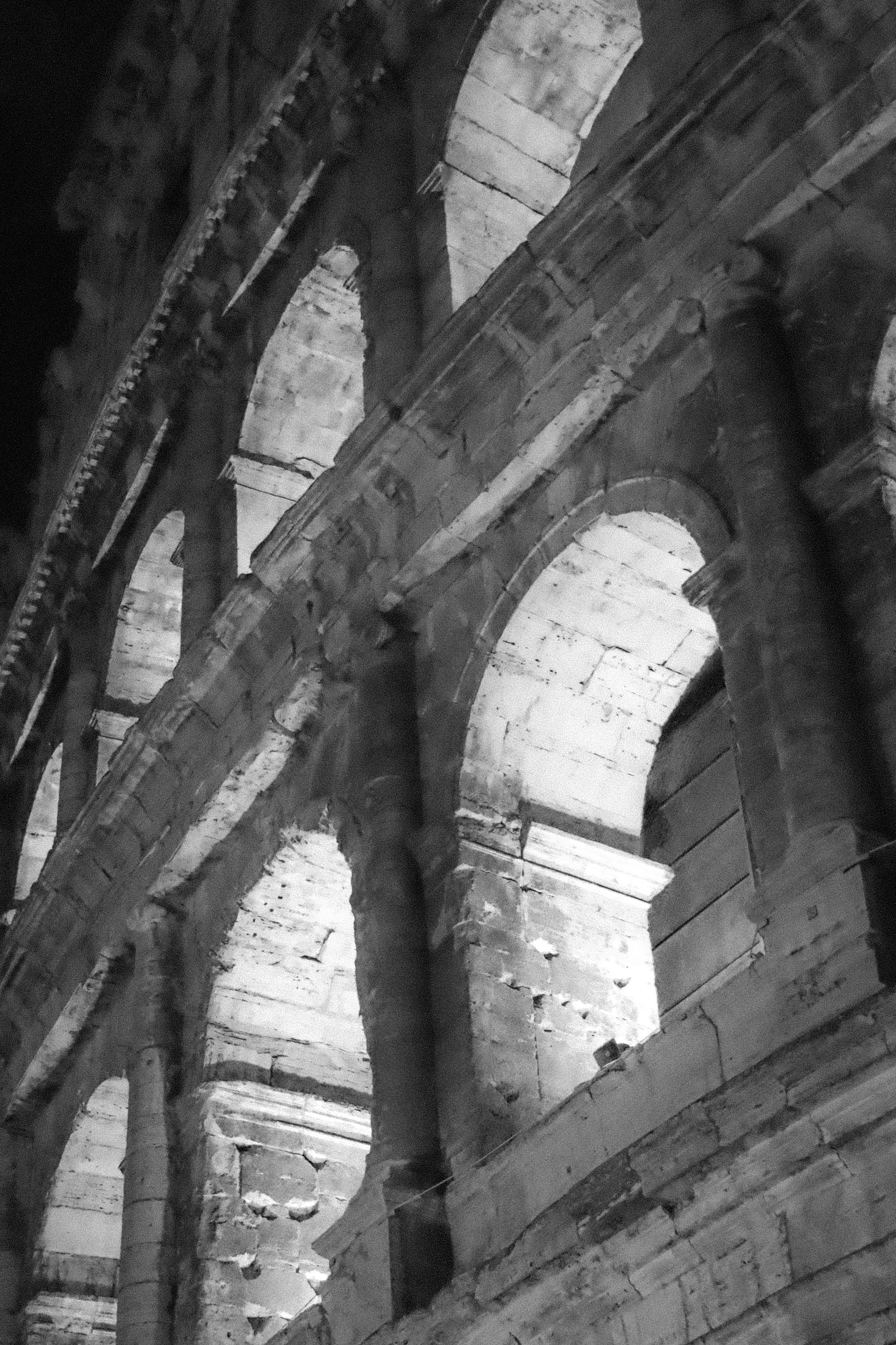 Vista laterale del Colosseo di notte con archi e struttura in pietra in evidenza