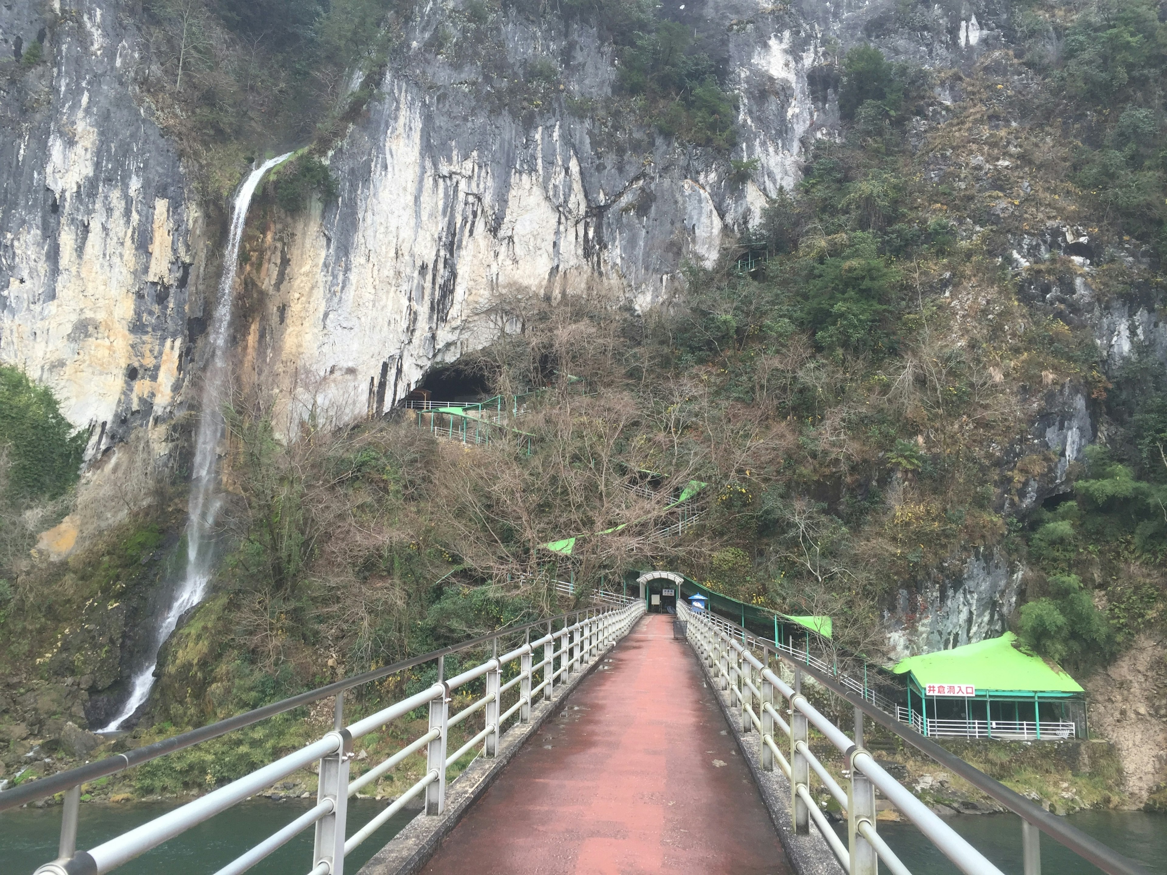 Bridge leading to a cave with a waterfall and rocky cliffs