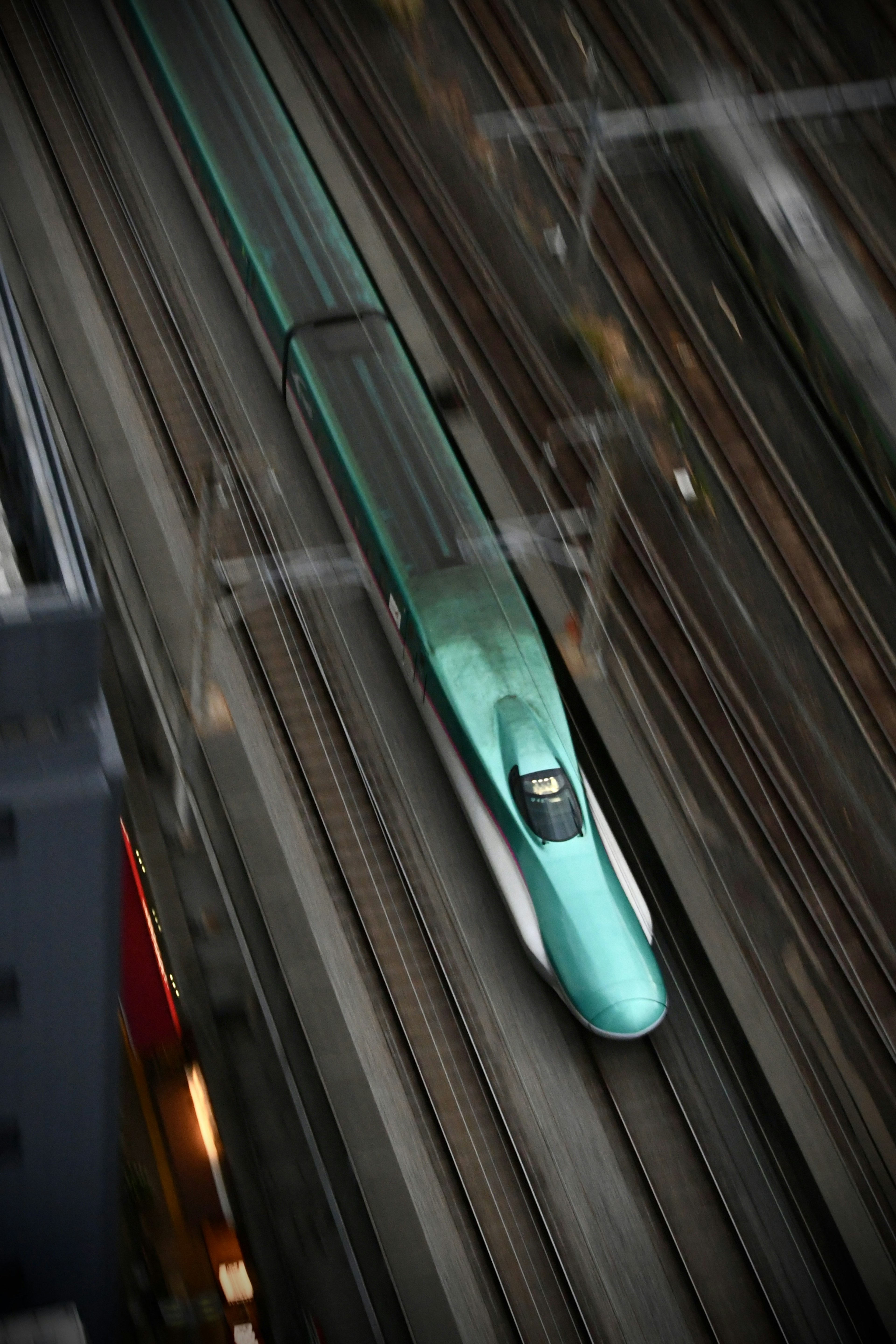 A blue Shinkansen train traveling on elevated tracks