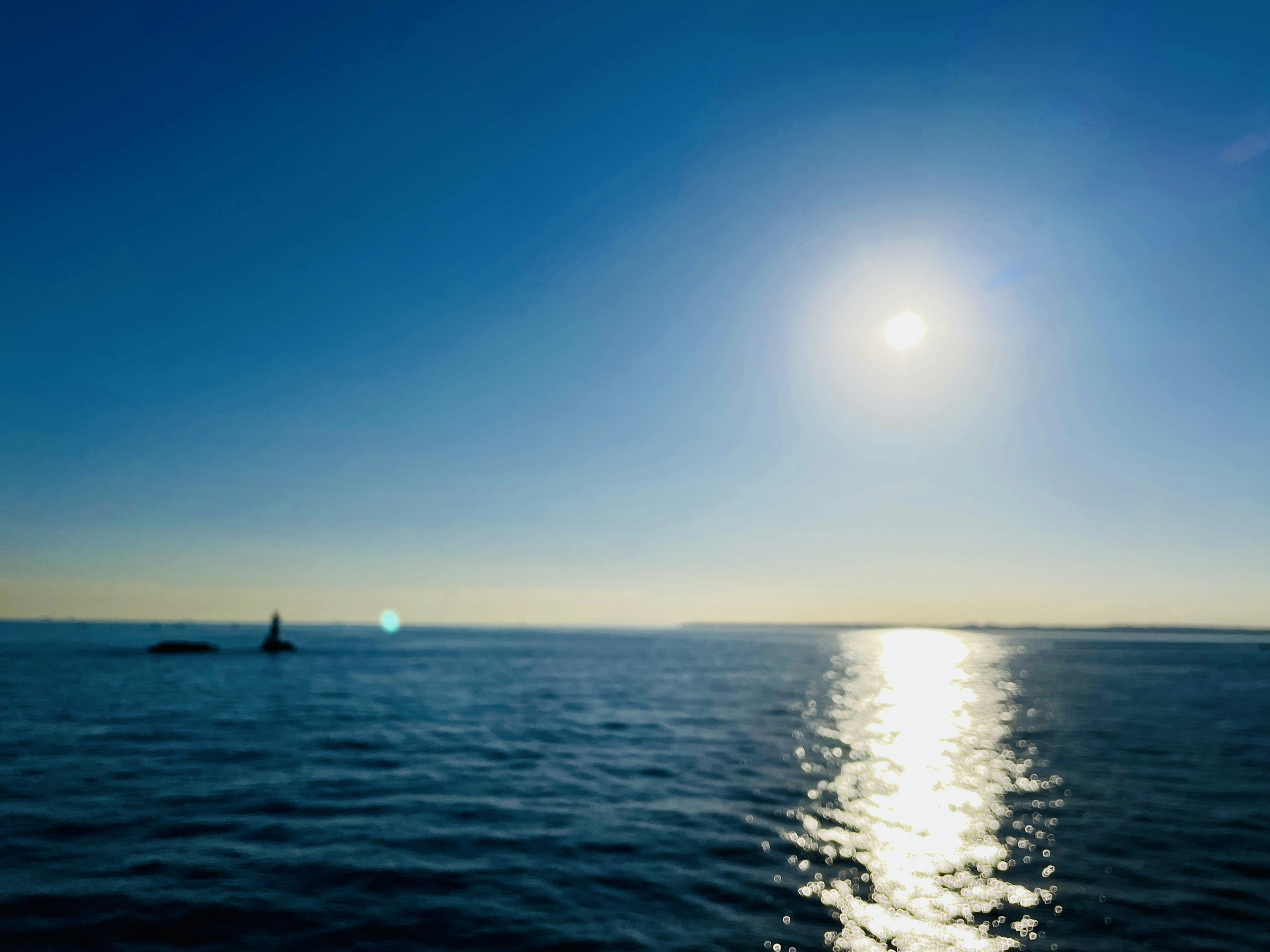 Vue panoramique de l'océan bleu réfléchissant la lumière du soleil sous un ciel dégagé