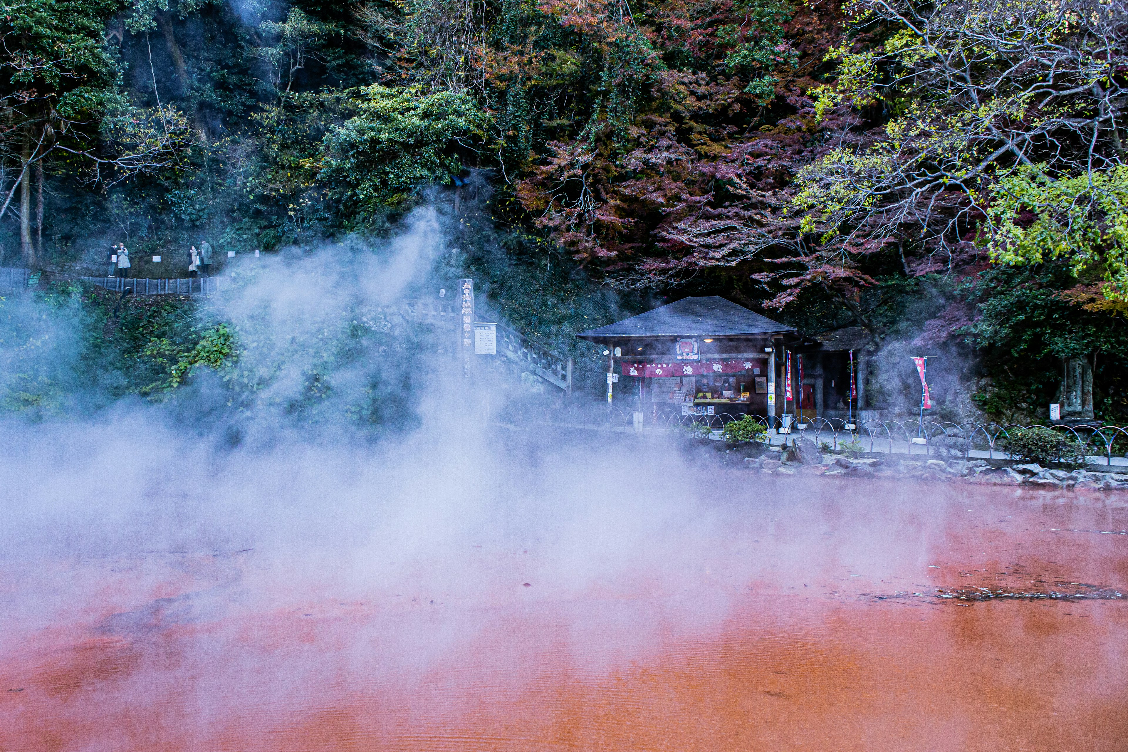 Red hot spring surrounded by mist and autumn foliage