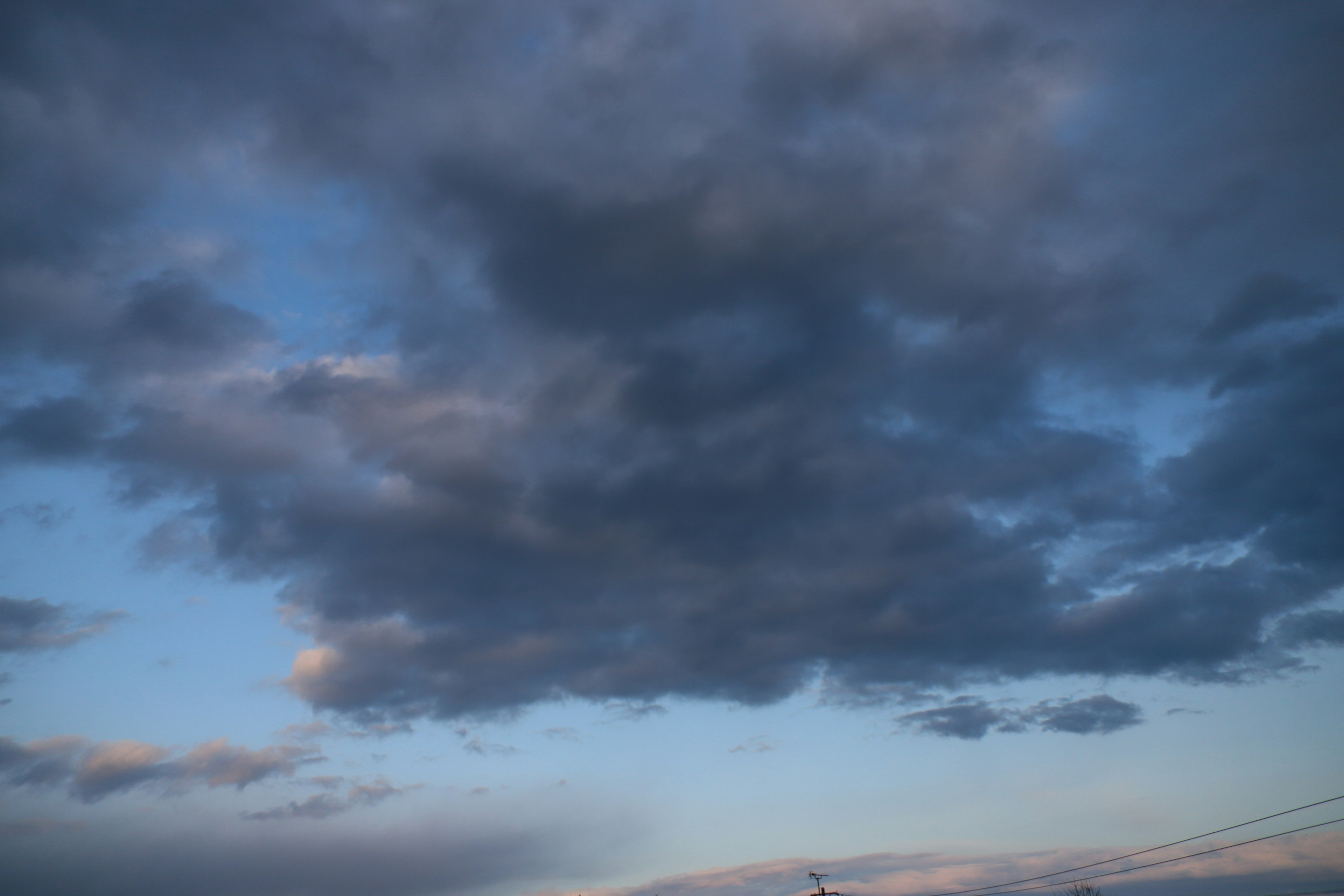 Nubes oscuras flotando en un cielo azul con iluminación crepuscular