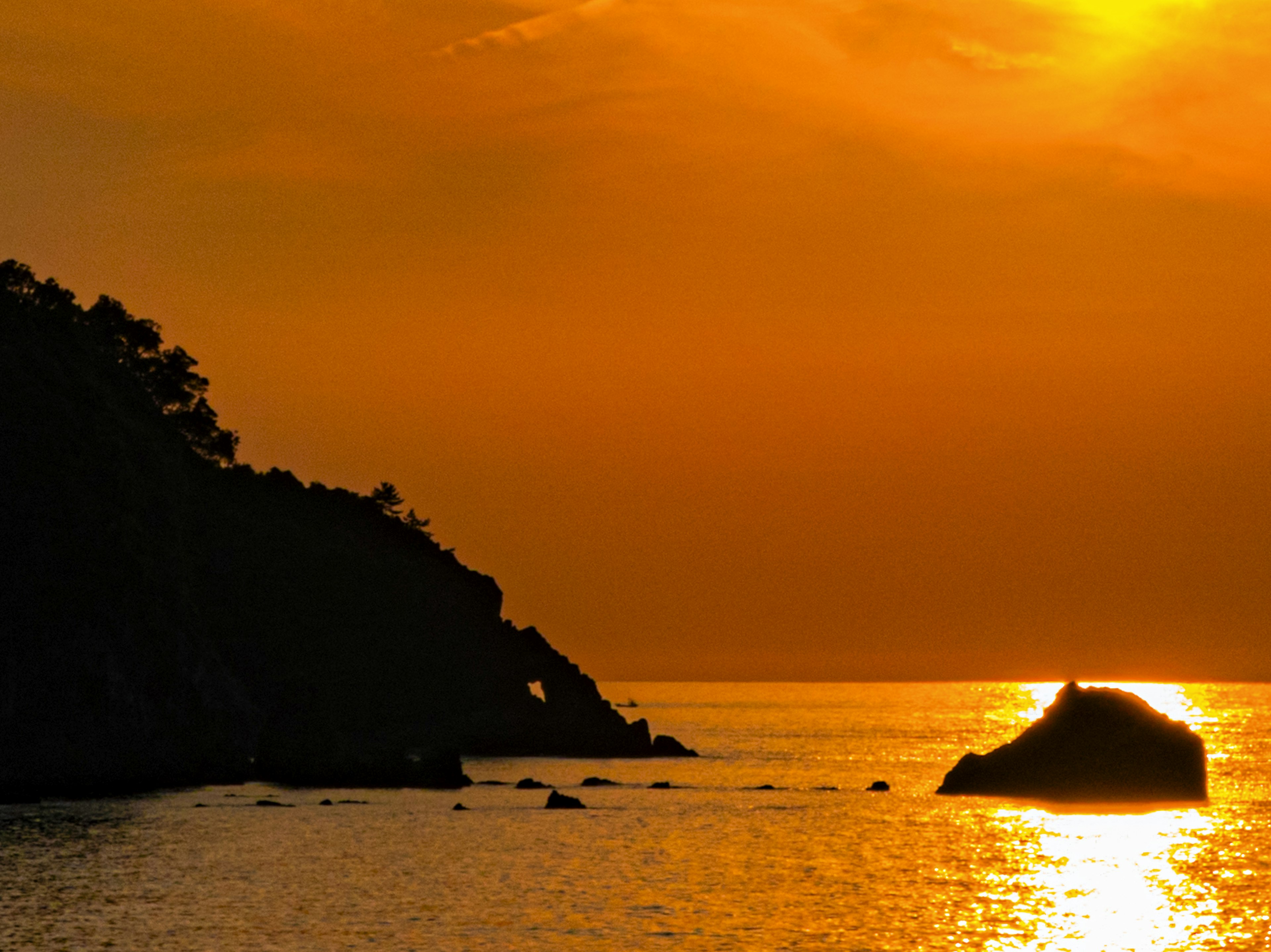 Schöner Sonnenuntergang über dem Ozean mit Silhouetten von Felsen