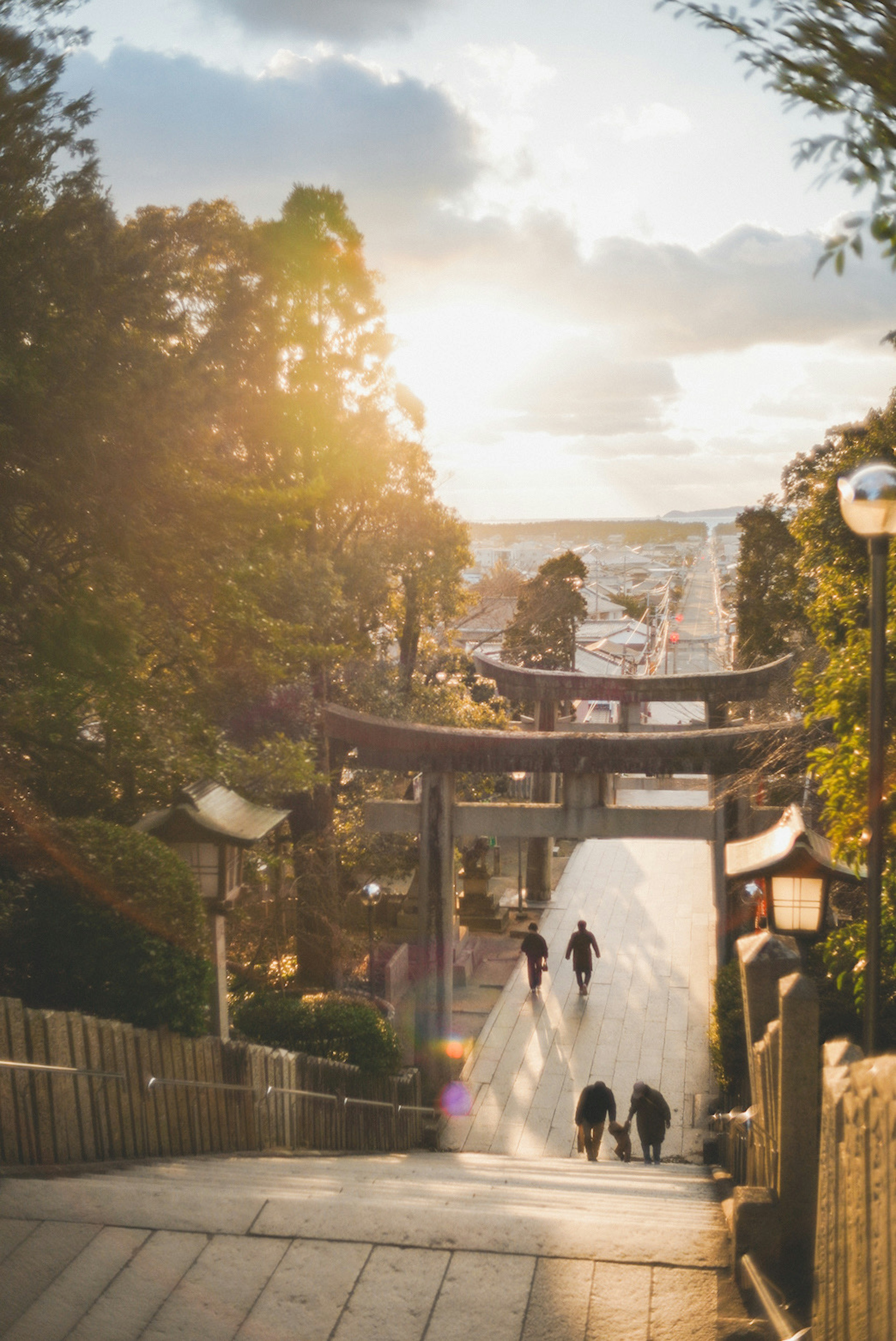 夕日を背景にした神社の階段と参拝者たち