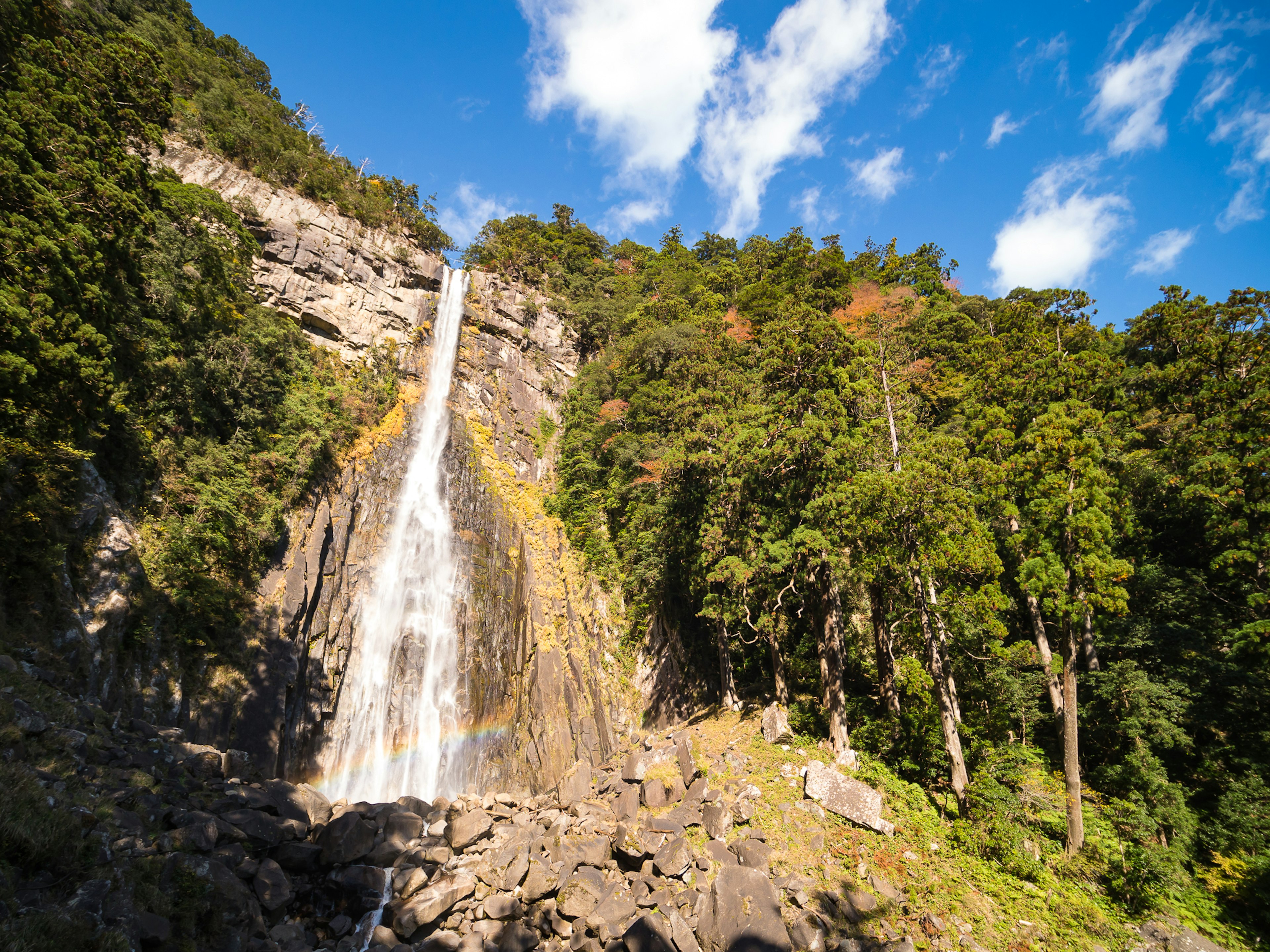 Una impresionante cascada que cae por acantilados rocosos rodeados de árboles verdes exuberantes