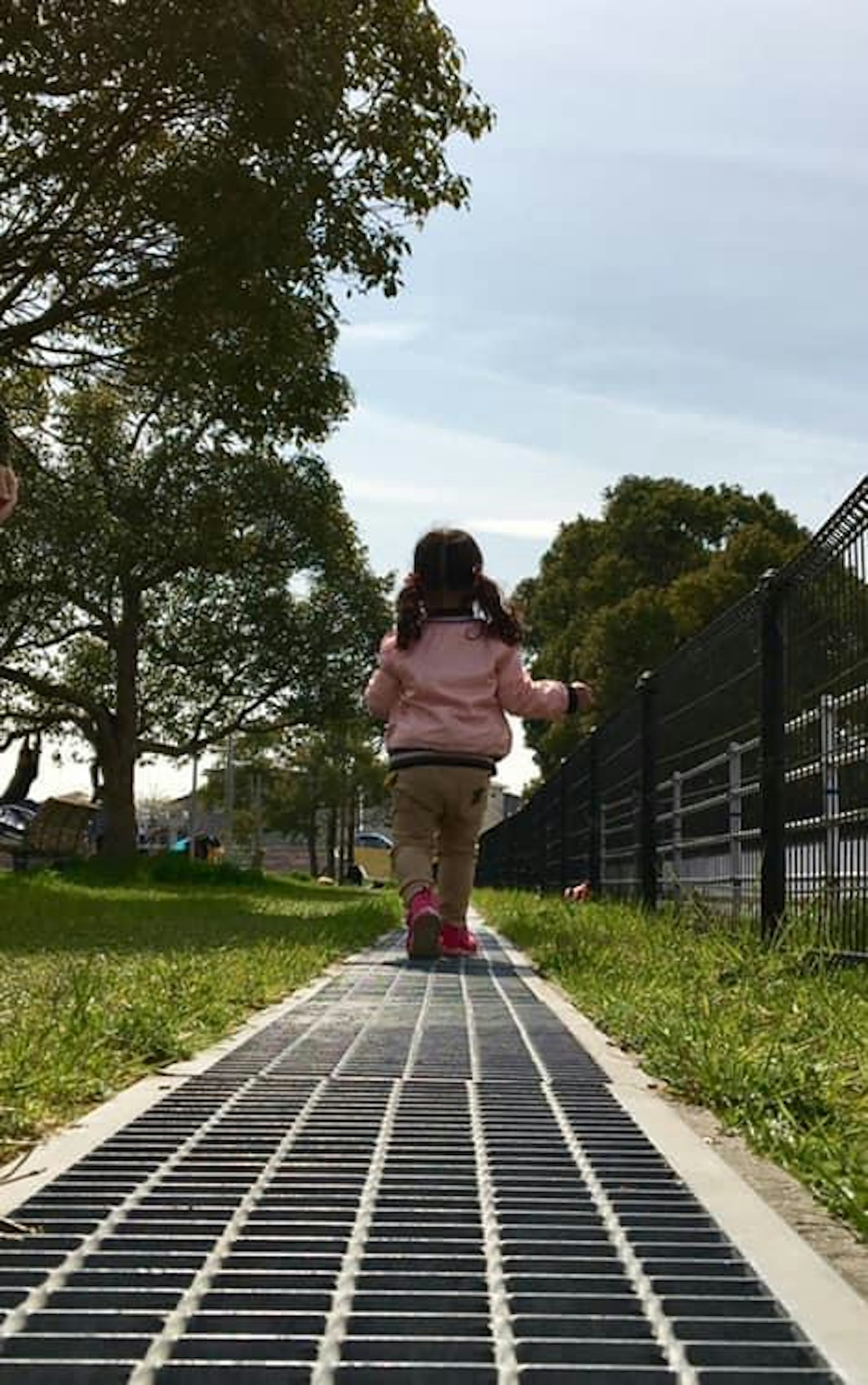 Una niña pequeña caminando por un camino del parque desde atrás