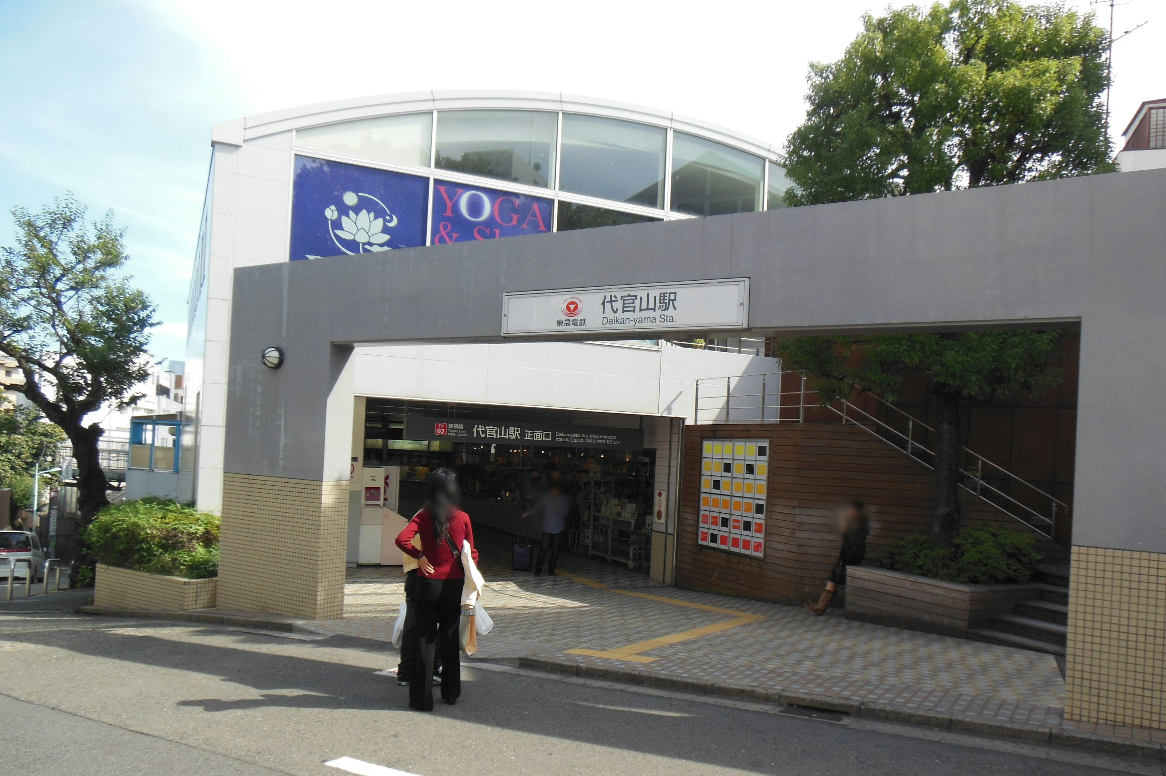 A view of a train station entrance with a person walking holding a red bag