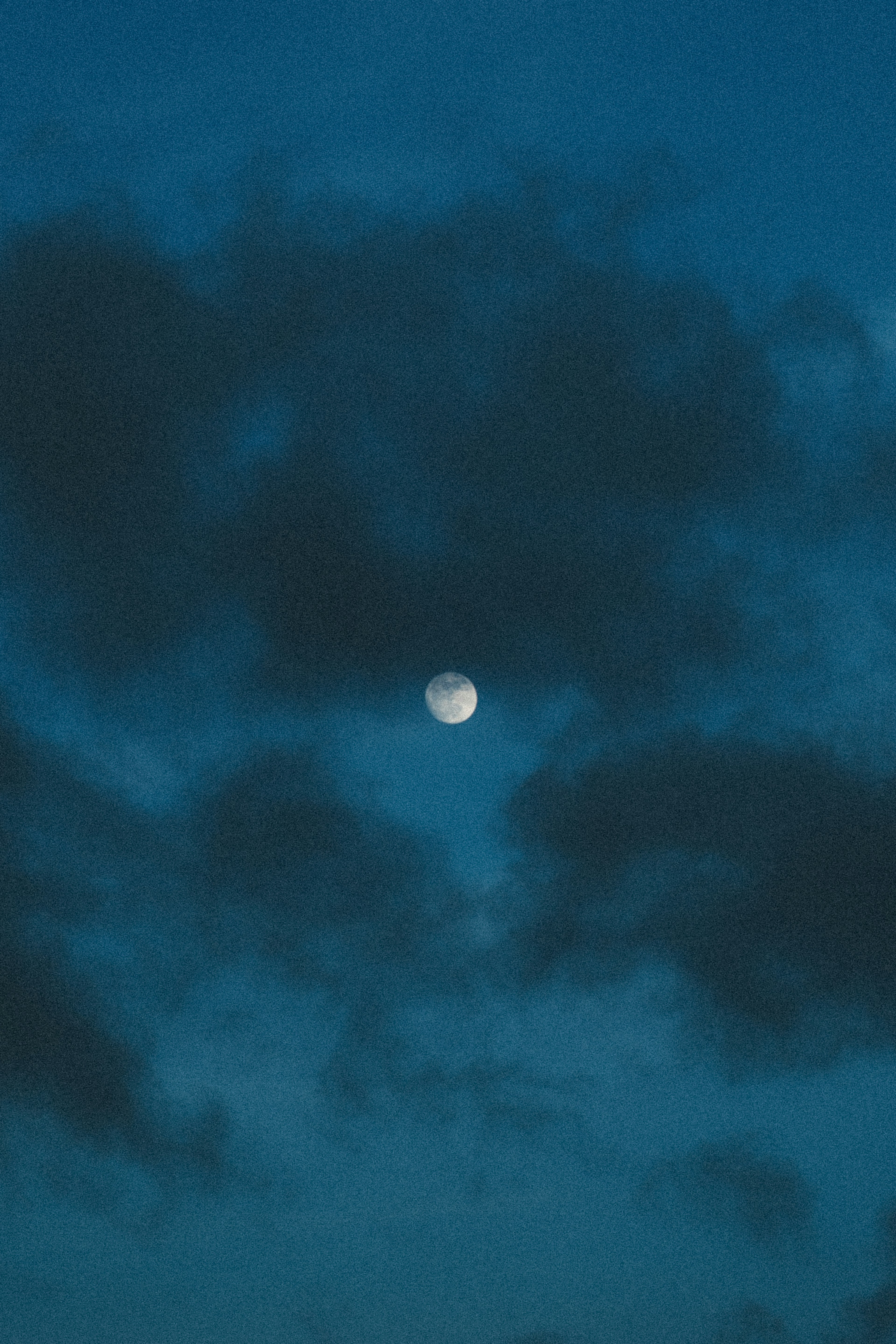 Lune partiellement obscurcie par des nuages sombres dans un ciel bleu