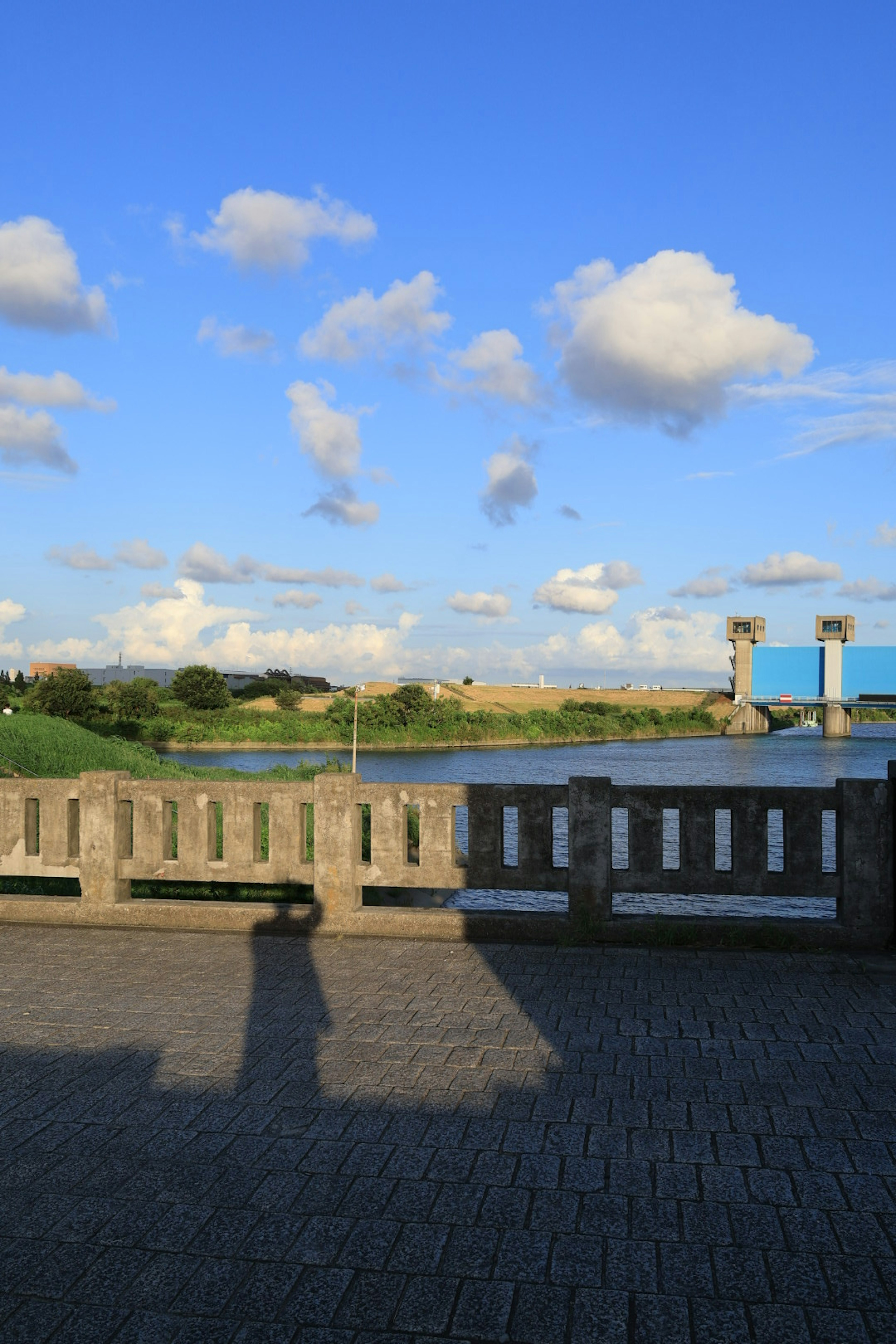 Vista escénica con cielo azul nubes un río y una barandilla de concreto