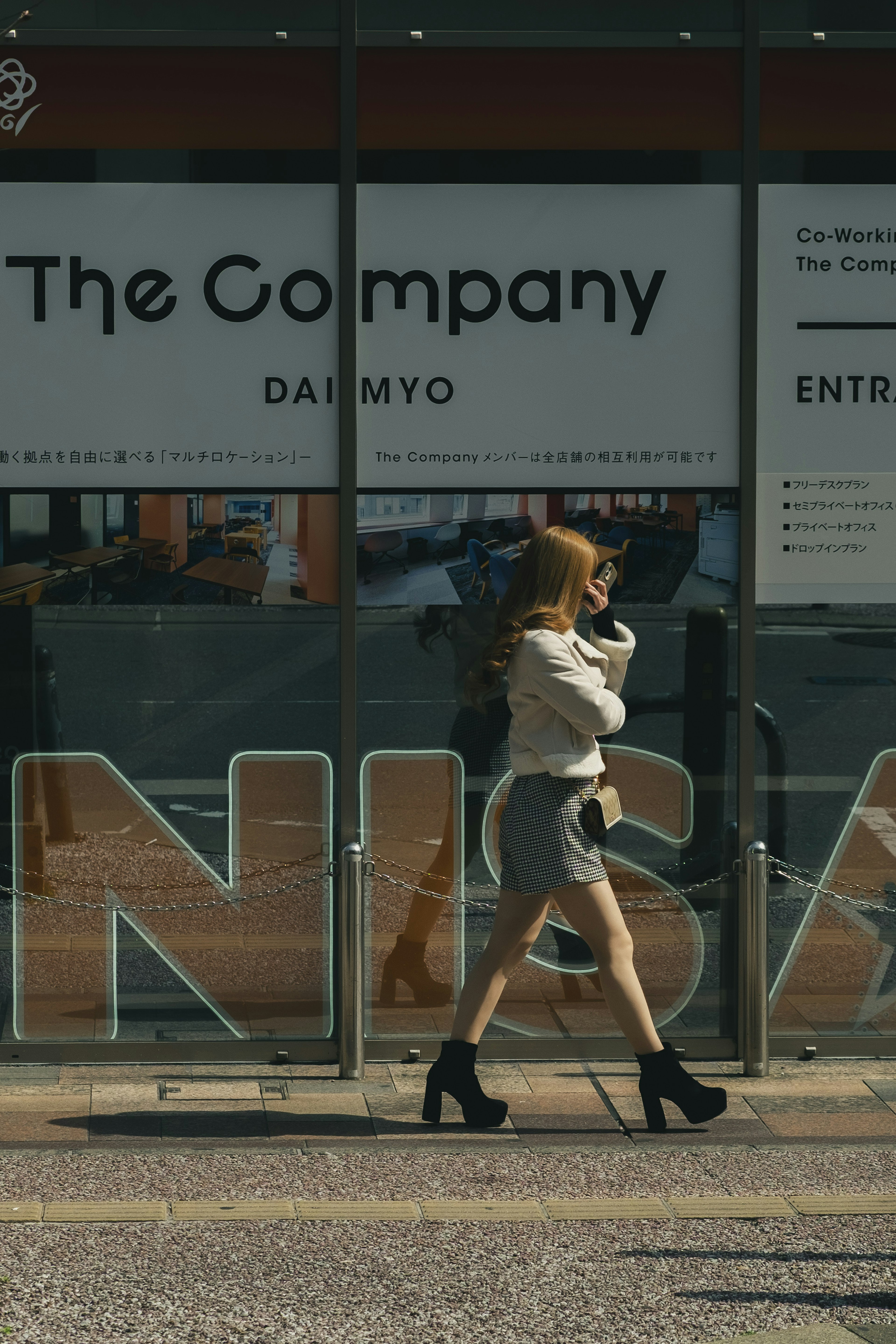 A woman in high heels walking past a store front with large letters