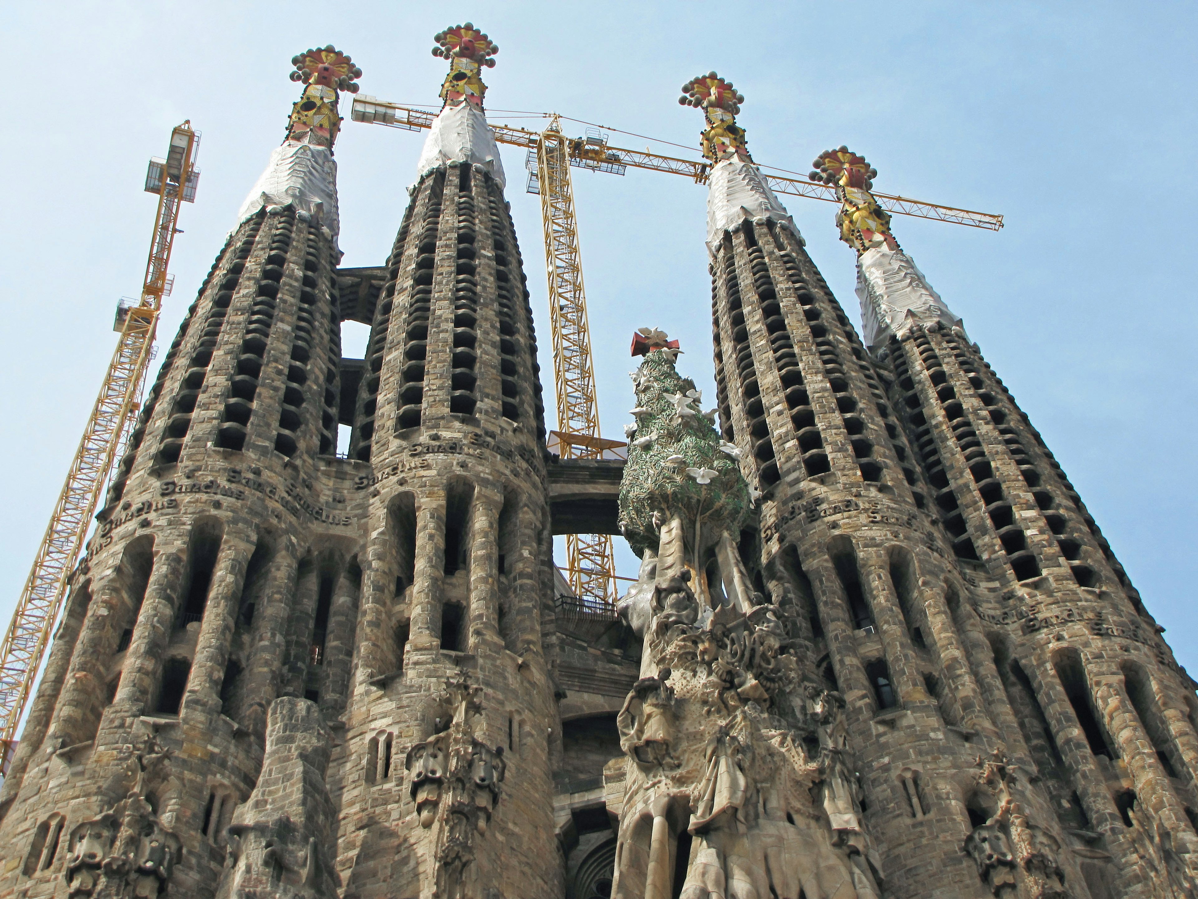 Imagen de las torres de la Sagrada Familia con grúas de construcción y esculturas intrincadas