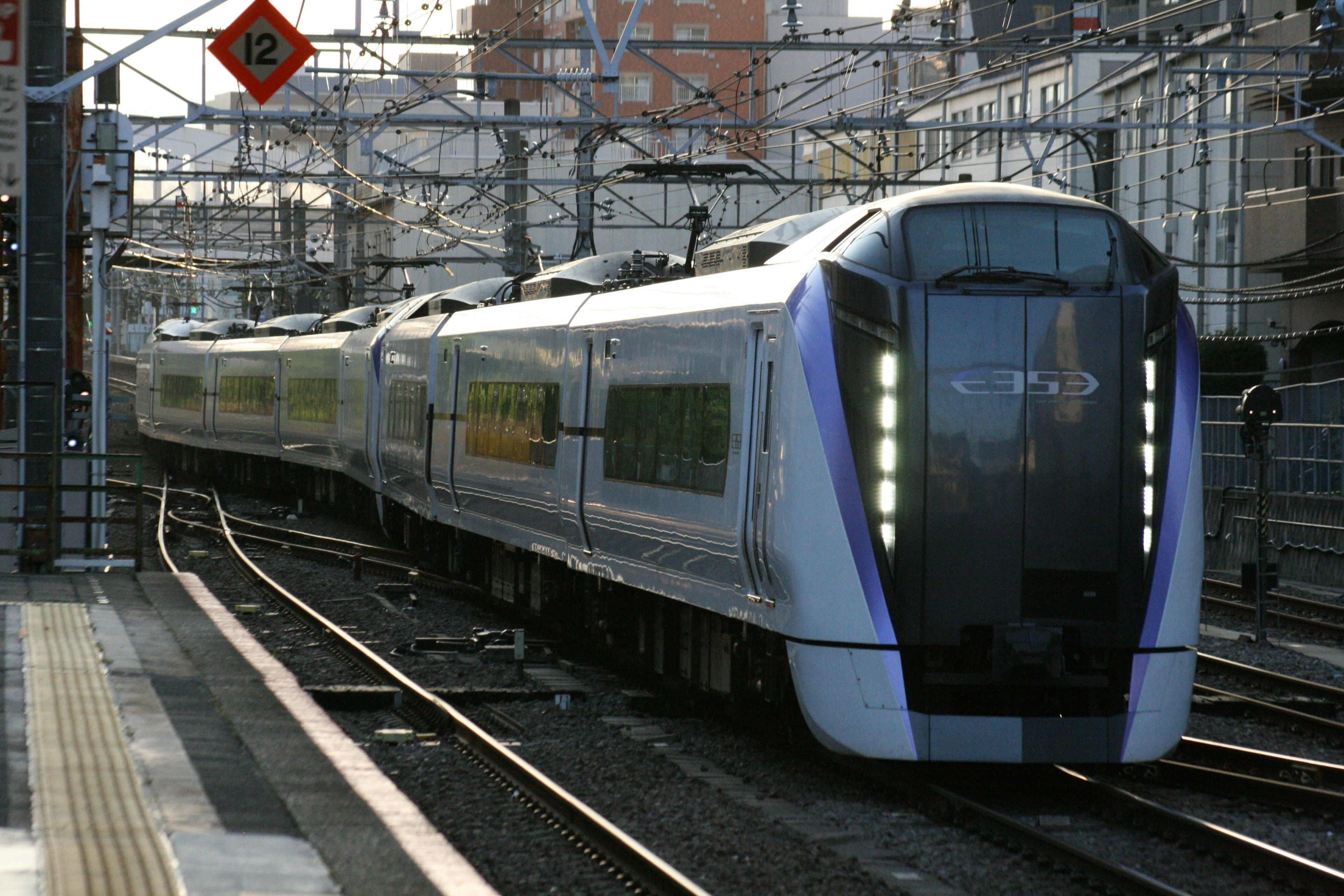 A modern train approaching a station with visible railway tracks and signals