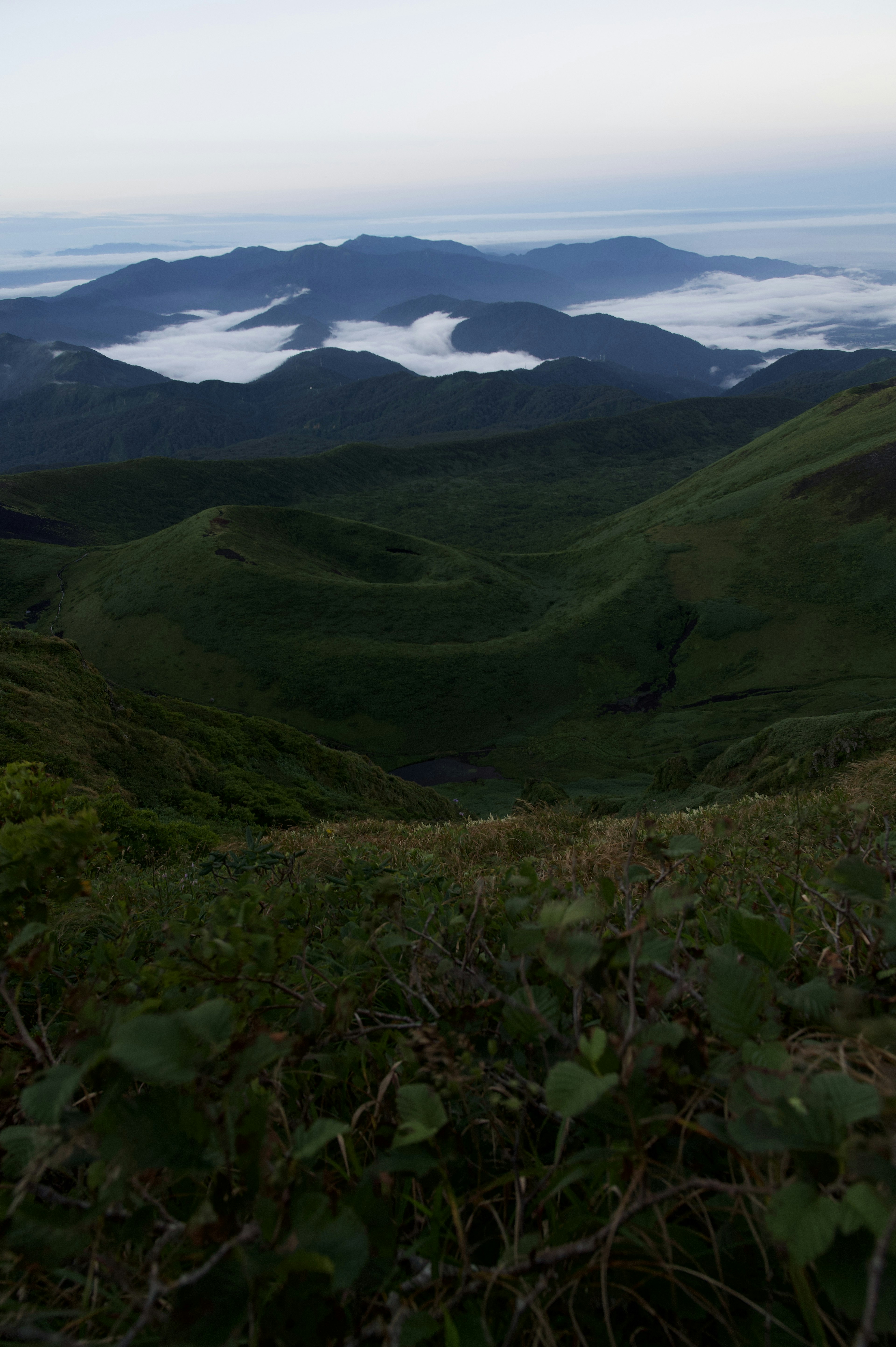 Scenic view of green hills and a sea of clouds