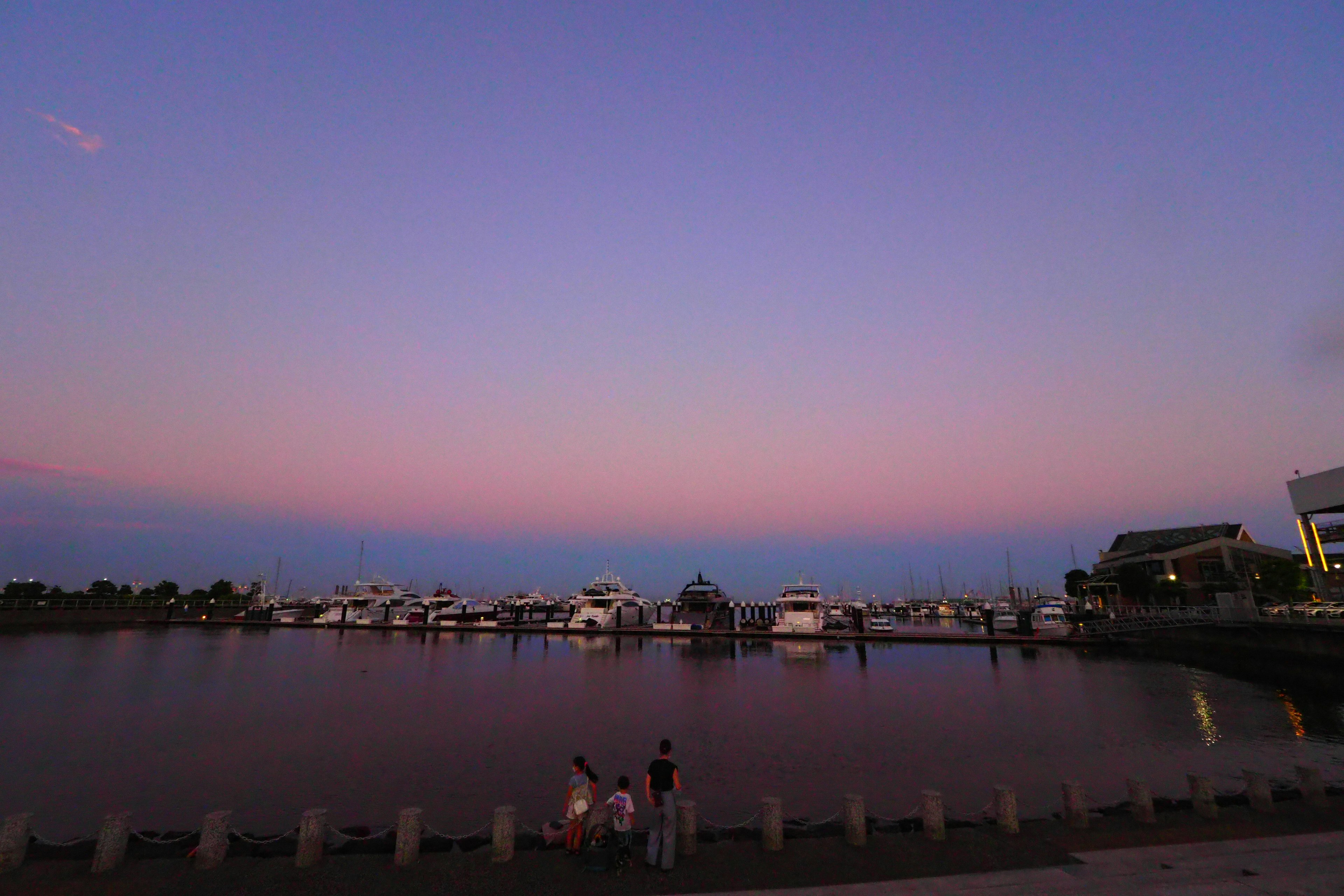 Pemandangan marina yang tenang saat senja dengan perahu di atas air tenang