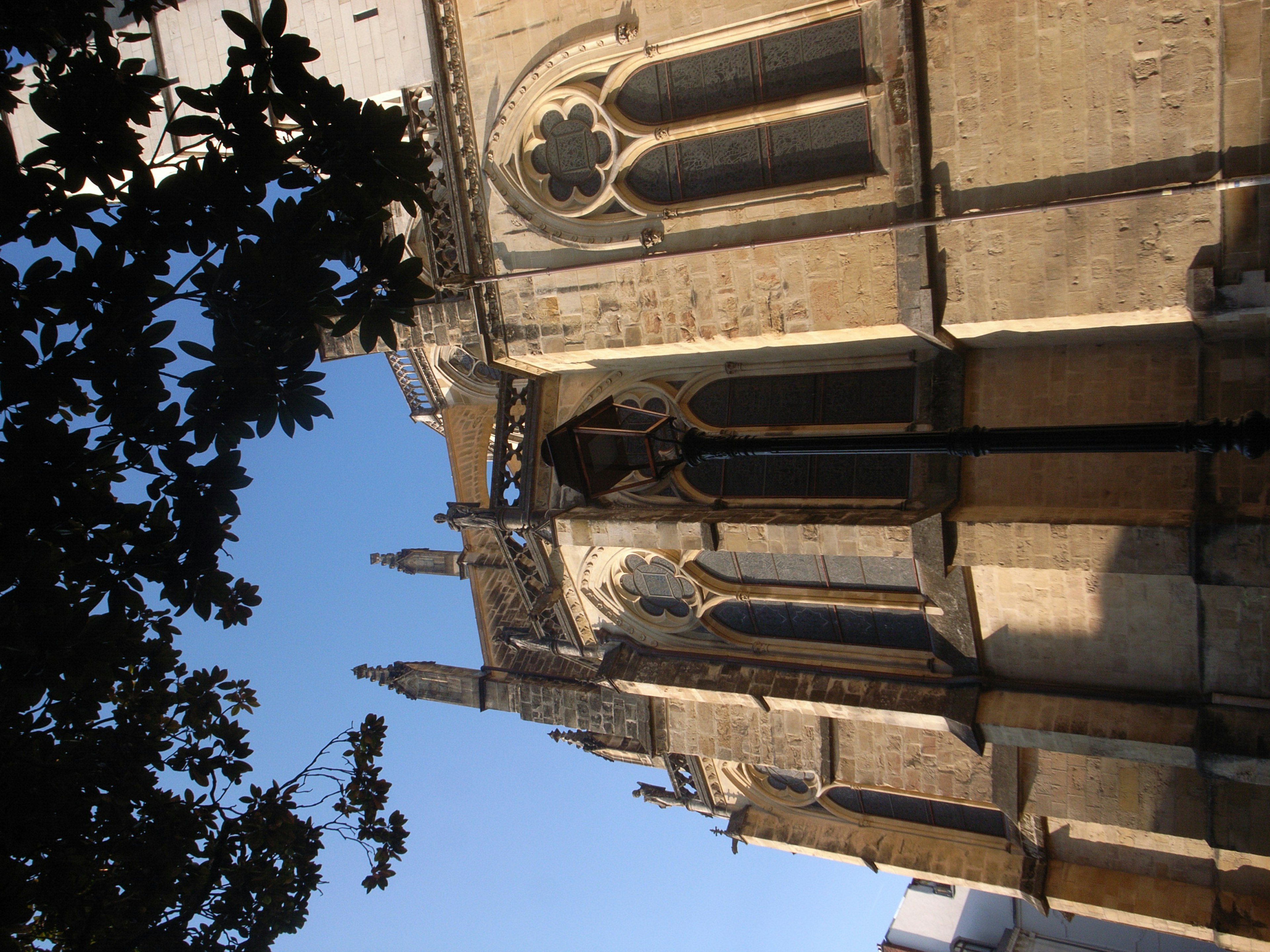 Beautiful Gothic architecture of a church exterior with blue sky and green leaves visible