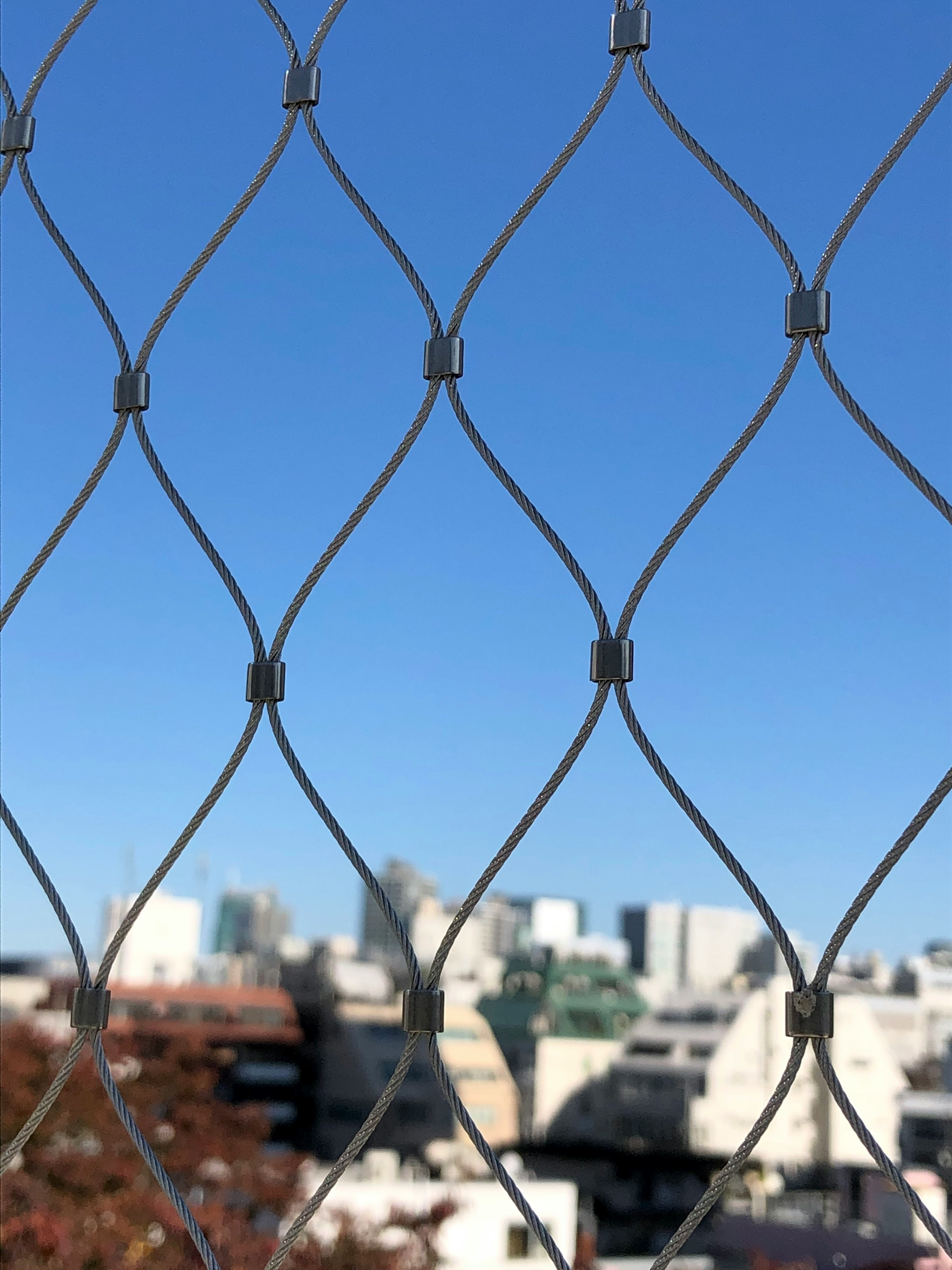 Close-up of a wire mesh fence against a blue sky