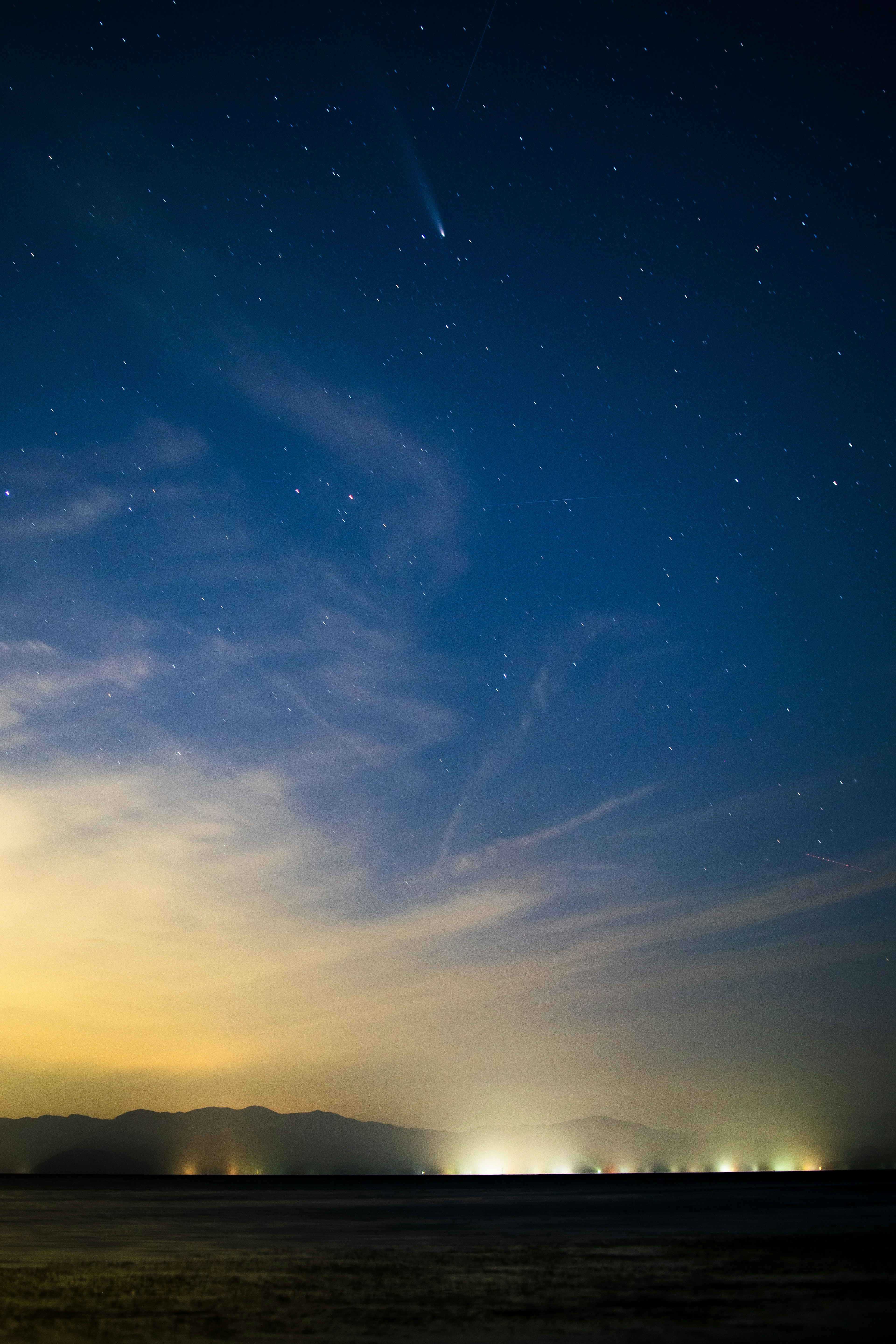 Cielo nocturno lleno de estrellas sobre un paisaje oscuro y nubes