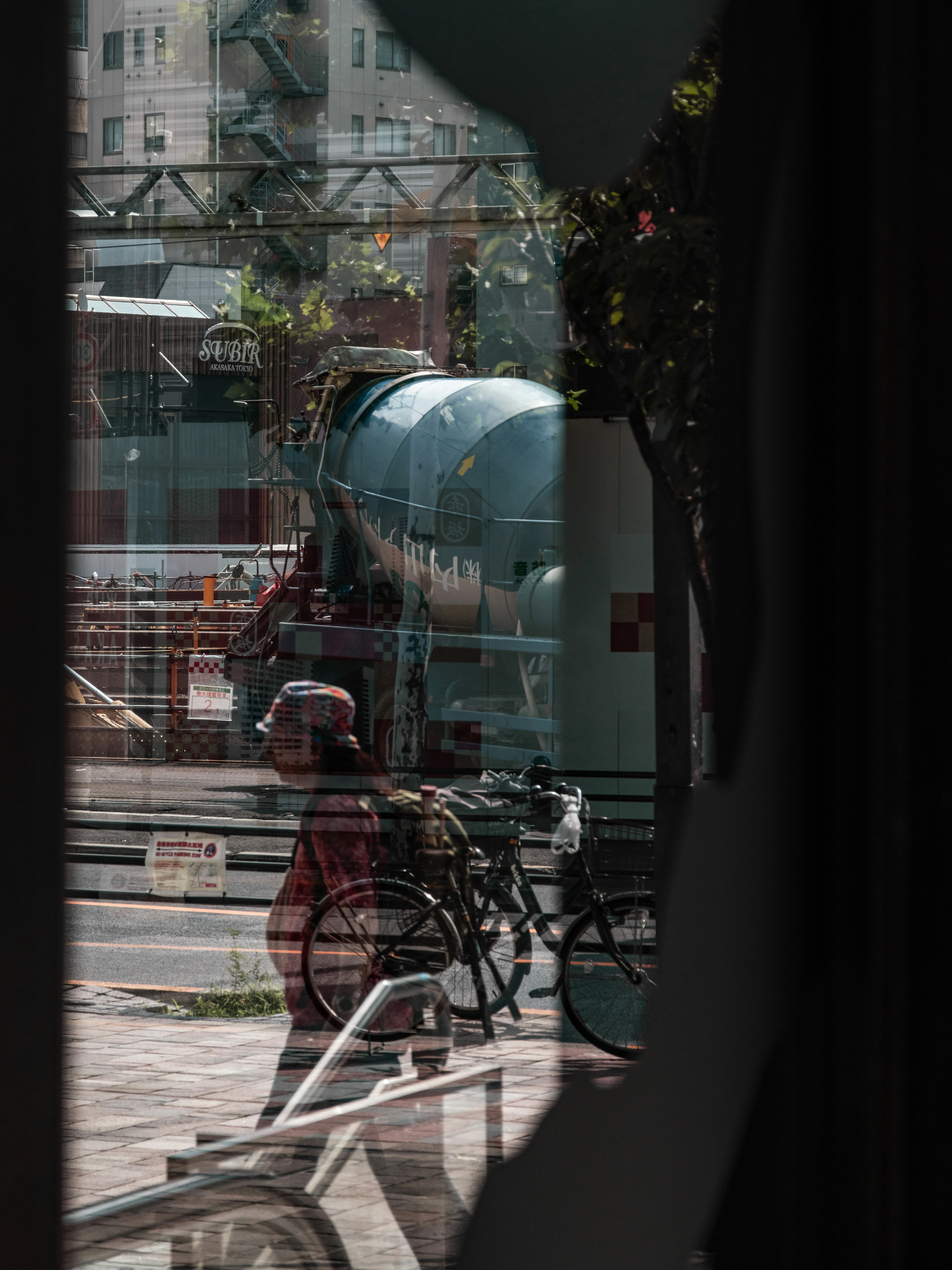 View of a construction site with a person walking a bicycle through a window
