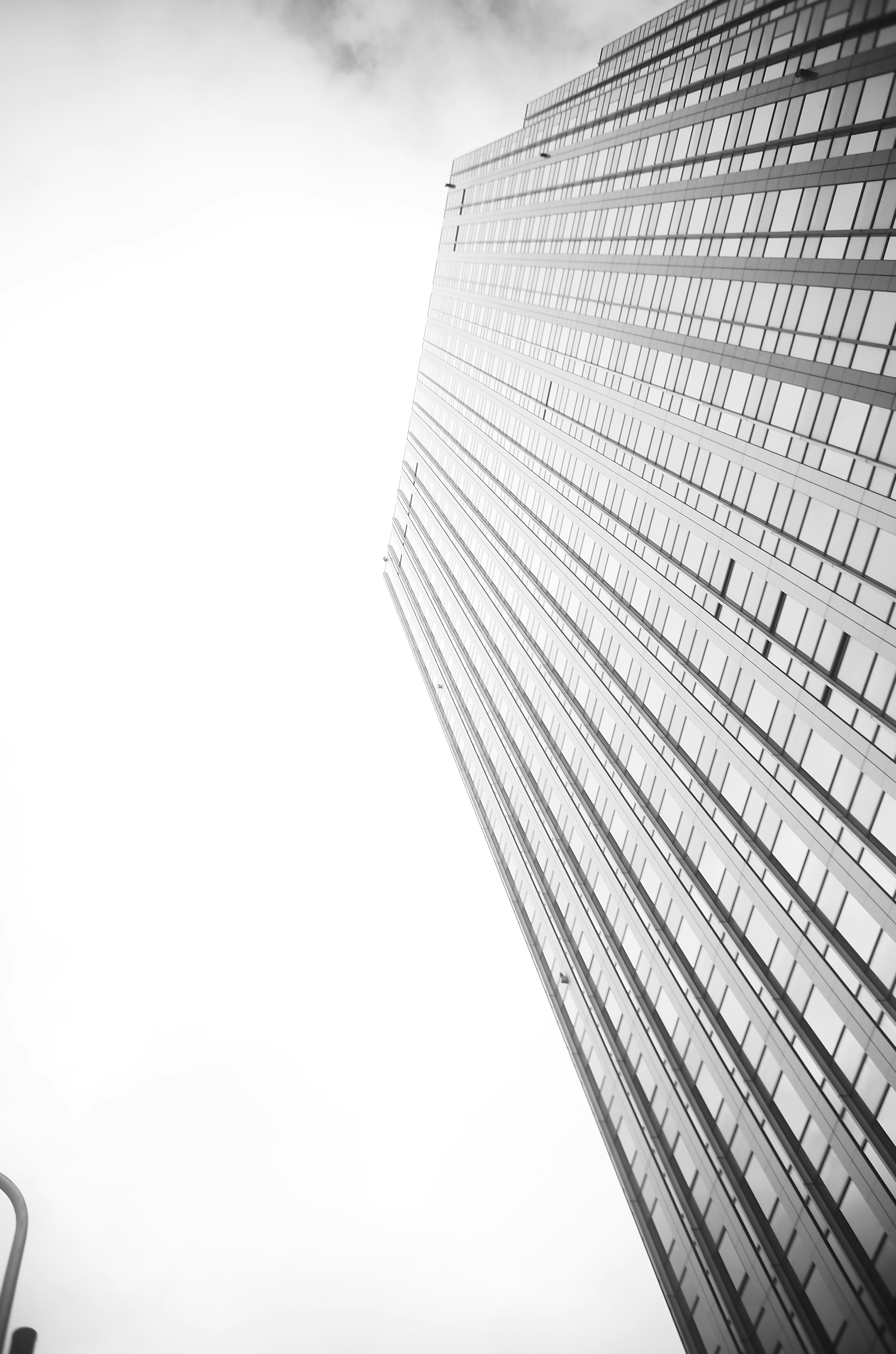 Skyscraper viewed from below with bright sky and clouds in the background