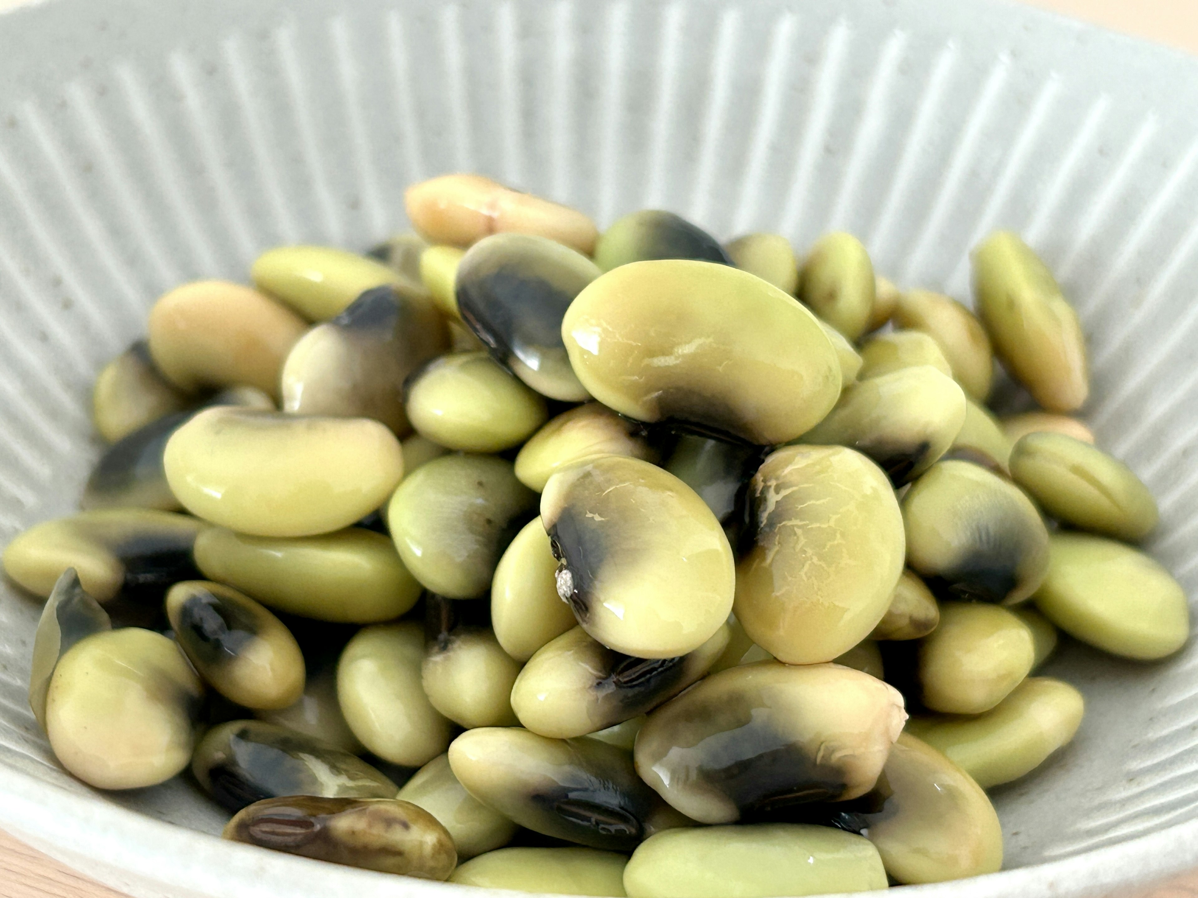 A pile of green and black beans in a light-colored bowl