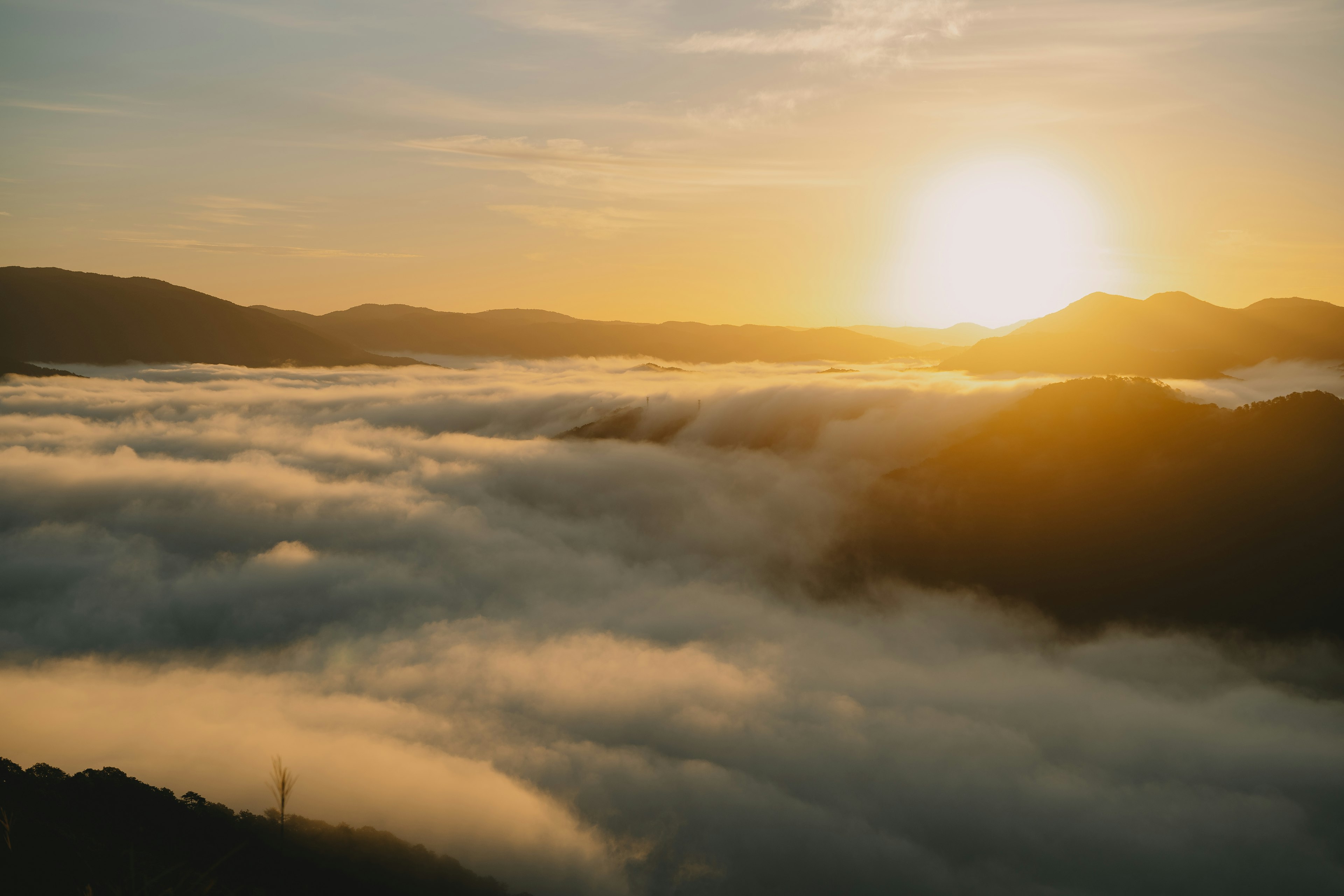 Amanecer sobre un mar de nubes con montañas al fondo