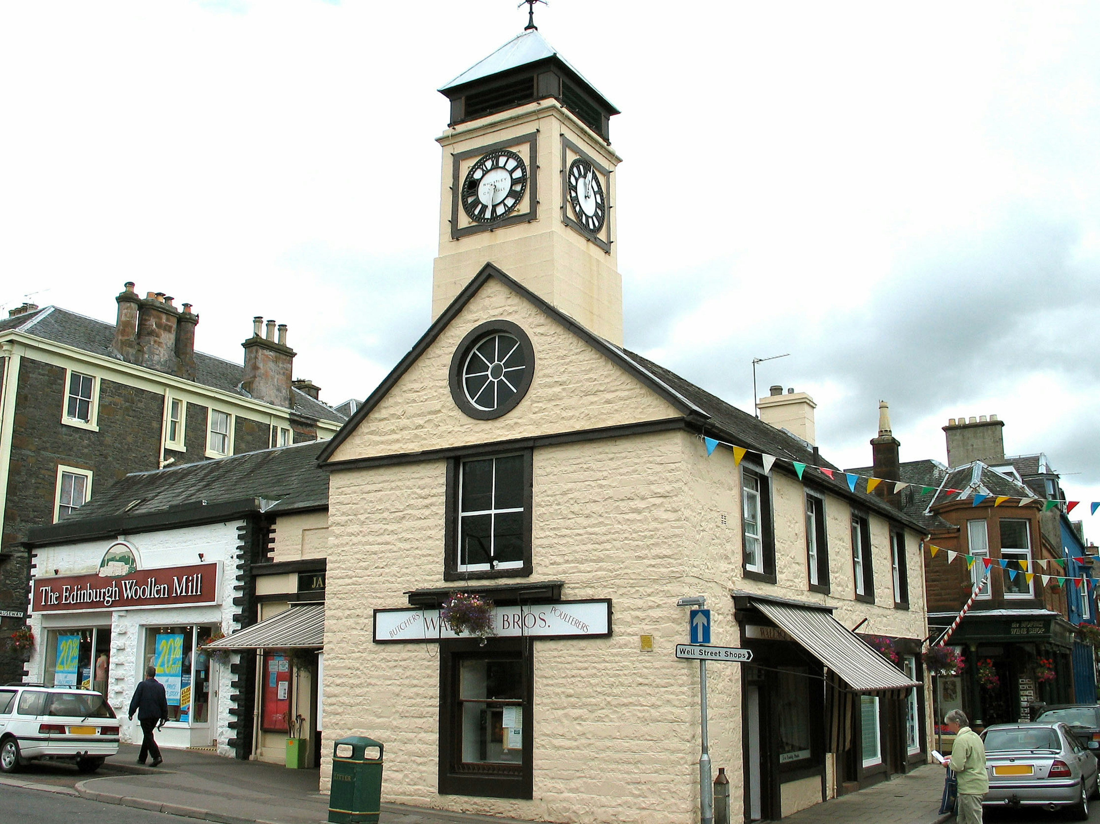 A white building with a clock tower and surrounding shops