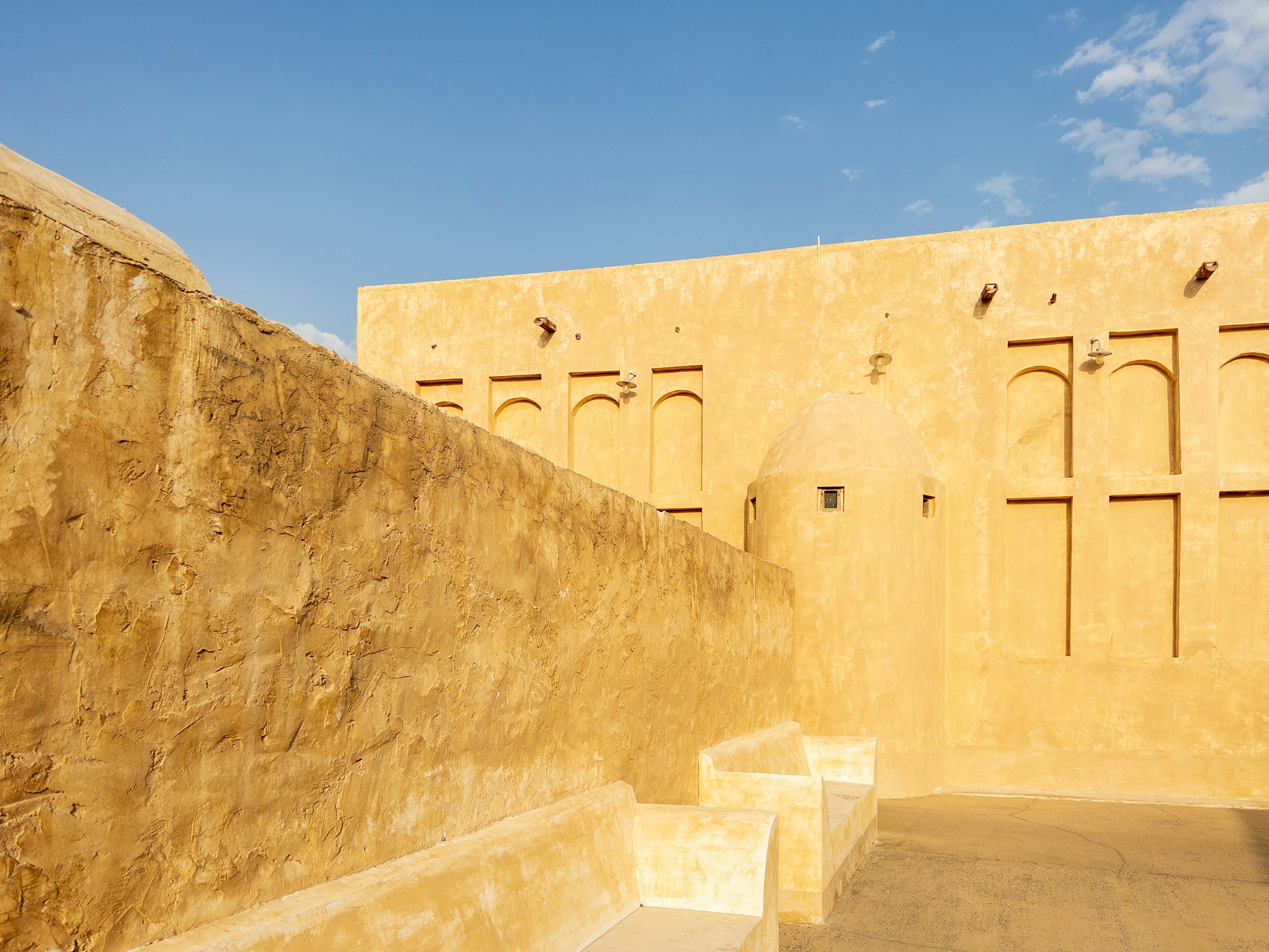 Interior view of an ancient building with sandy walls and a blue sky