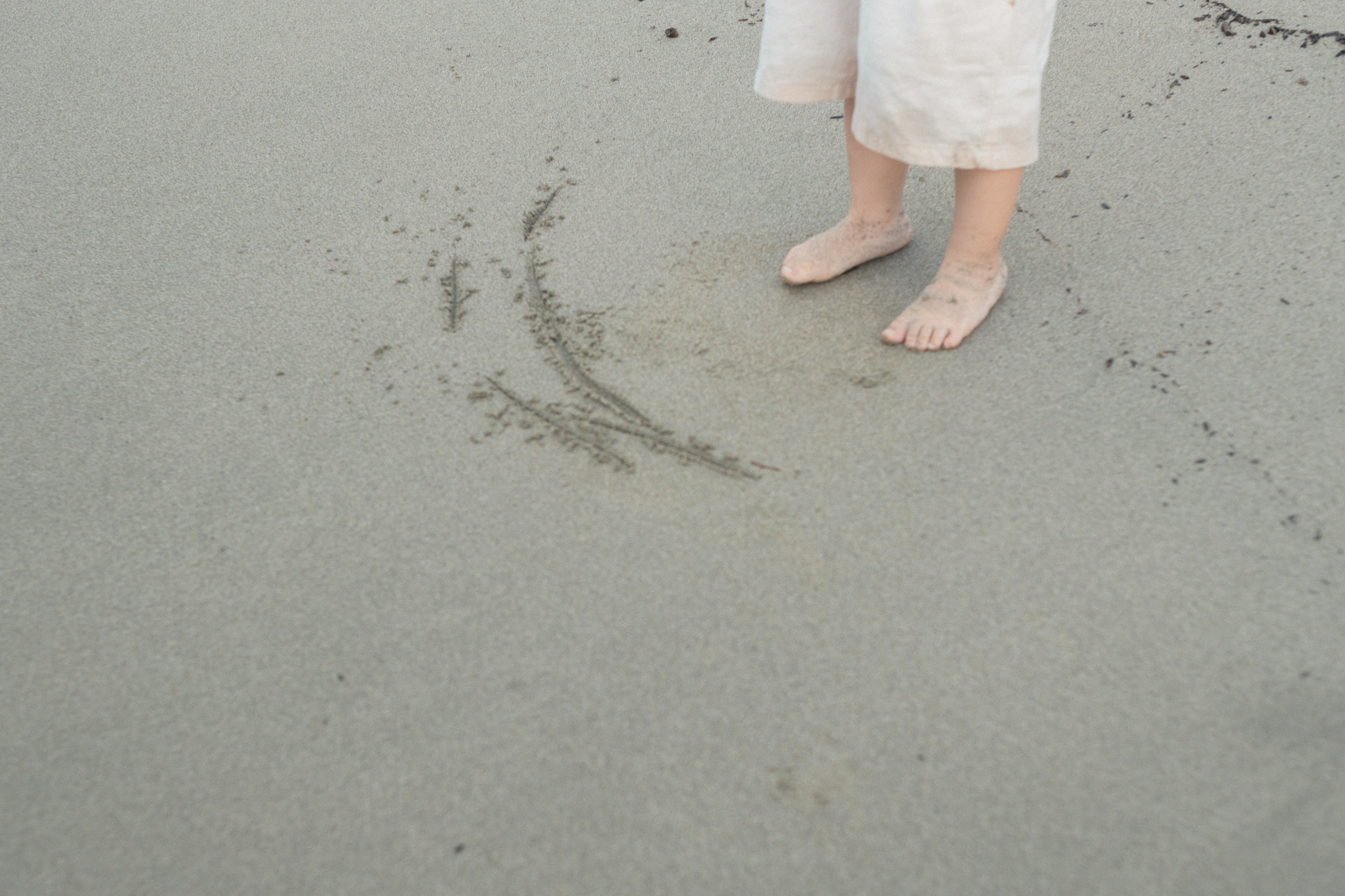 Barfußperson steht auf dem Sand mit Fußabdrücken