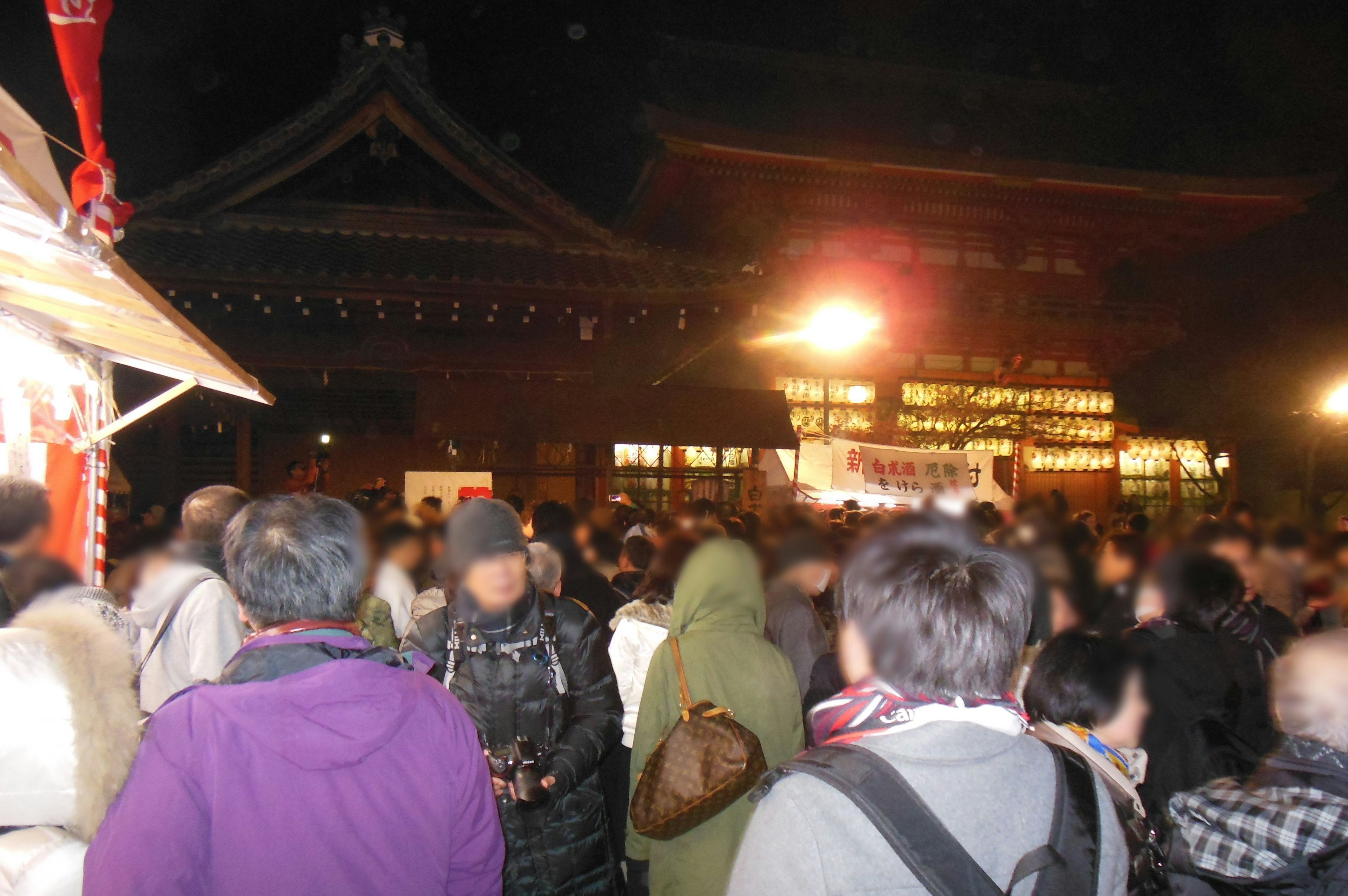 Crowd of people at a nighttime festival with illuminated buildings