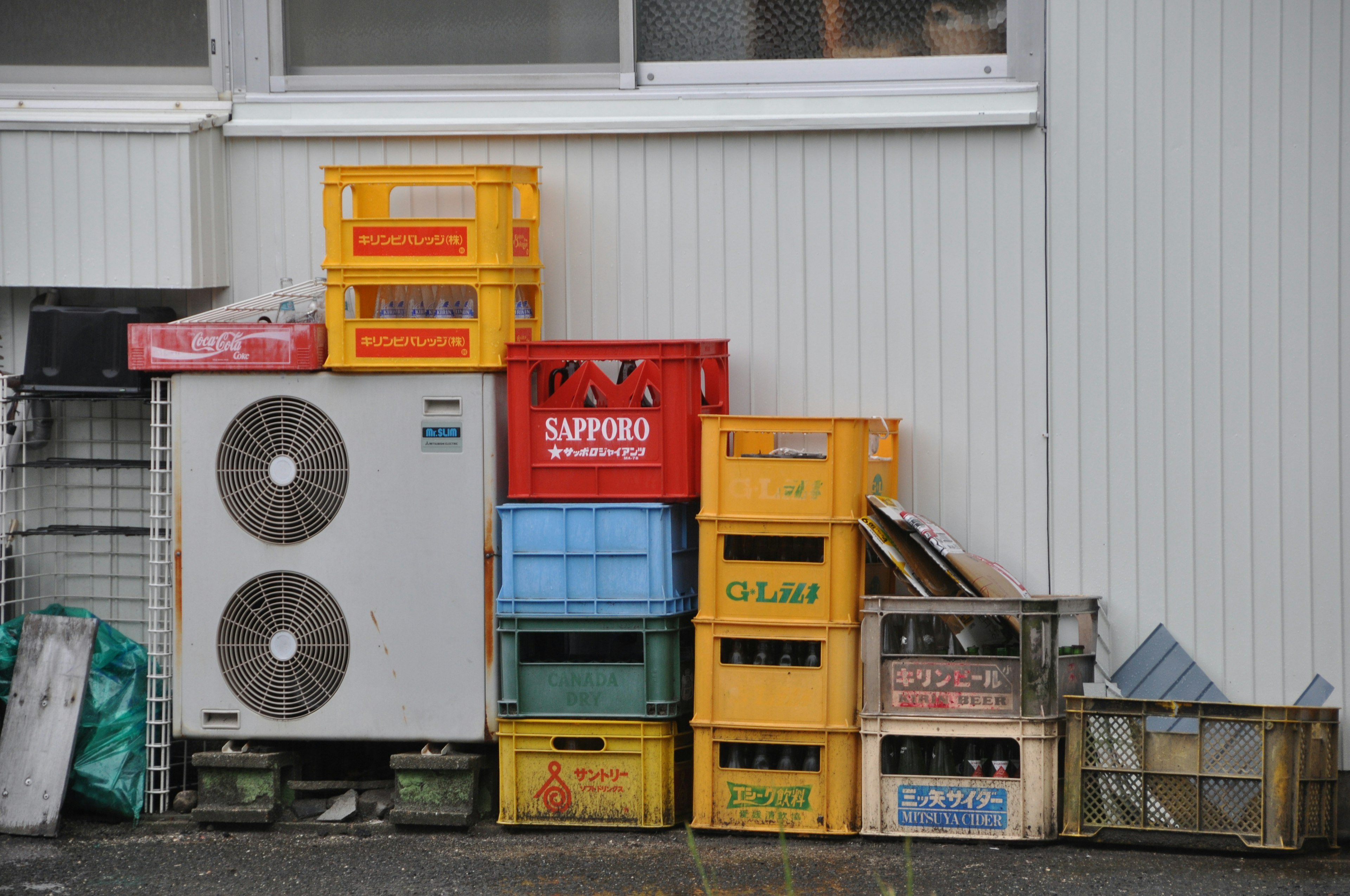 Colorful plastic and wooden crates stacked beside an air conditioning unit