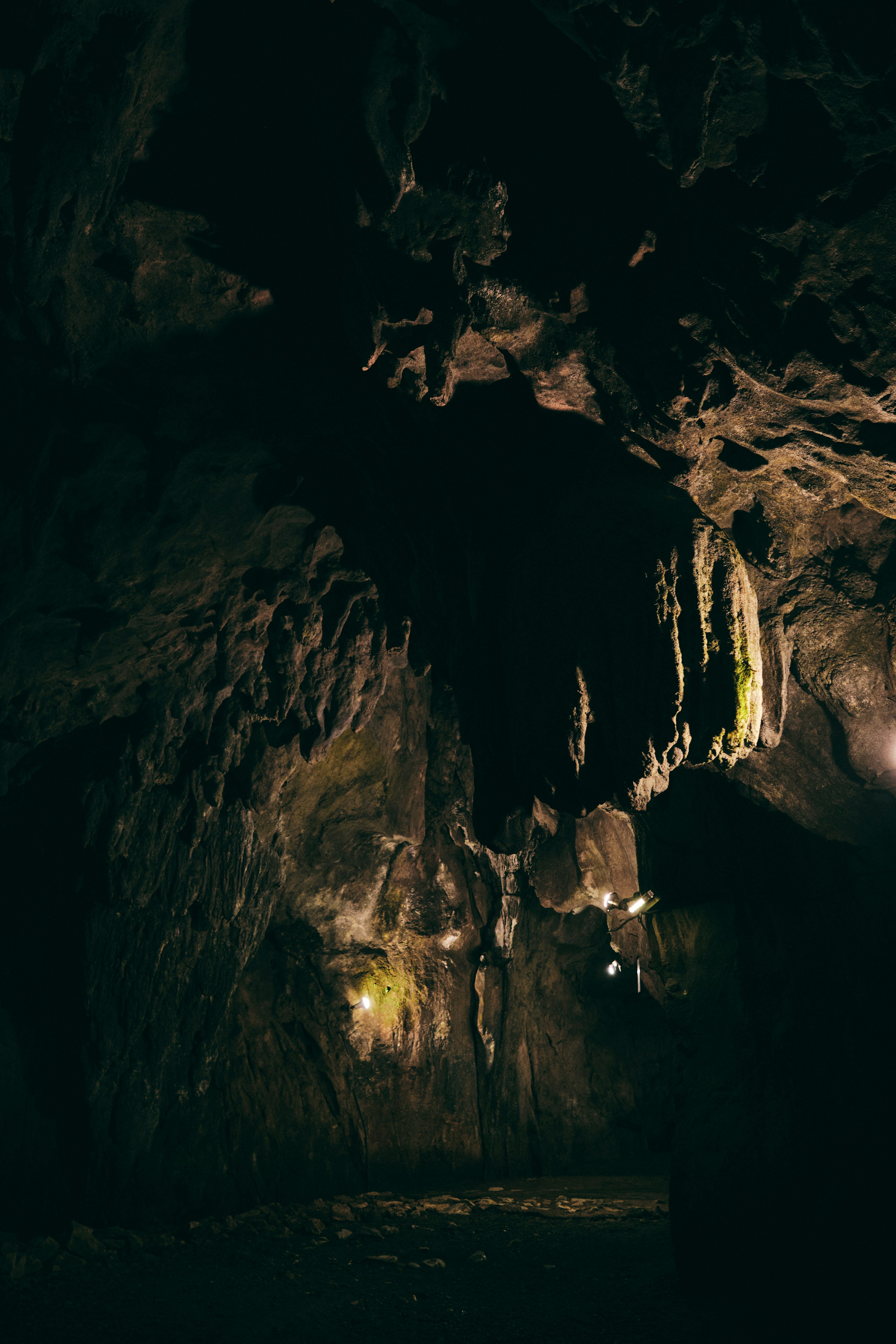 Interior de una cueva oscura con formaciones rocosas únicas y estalactitas