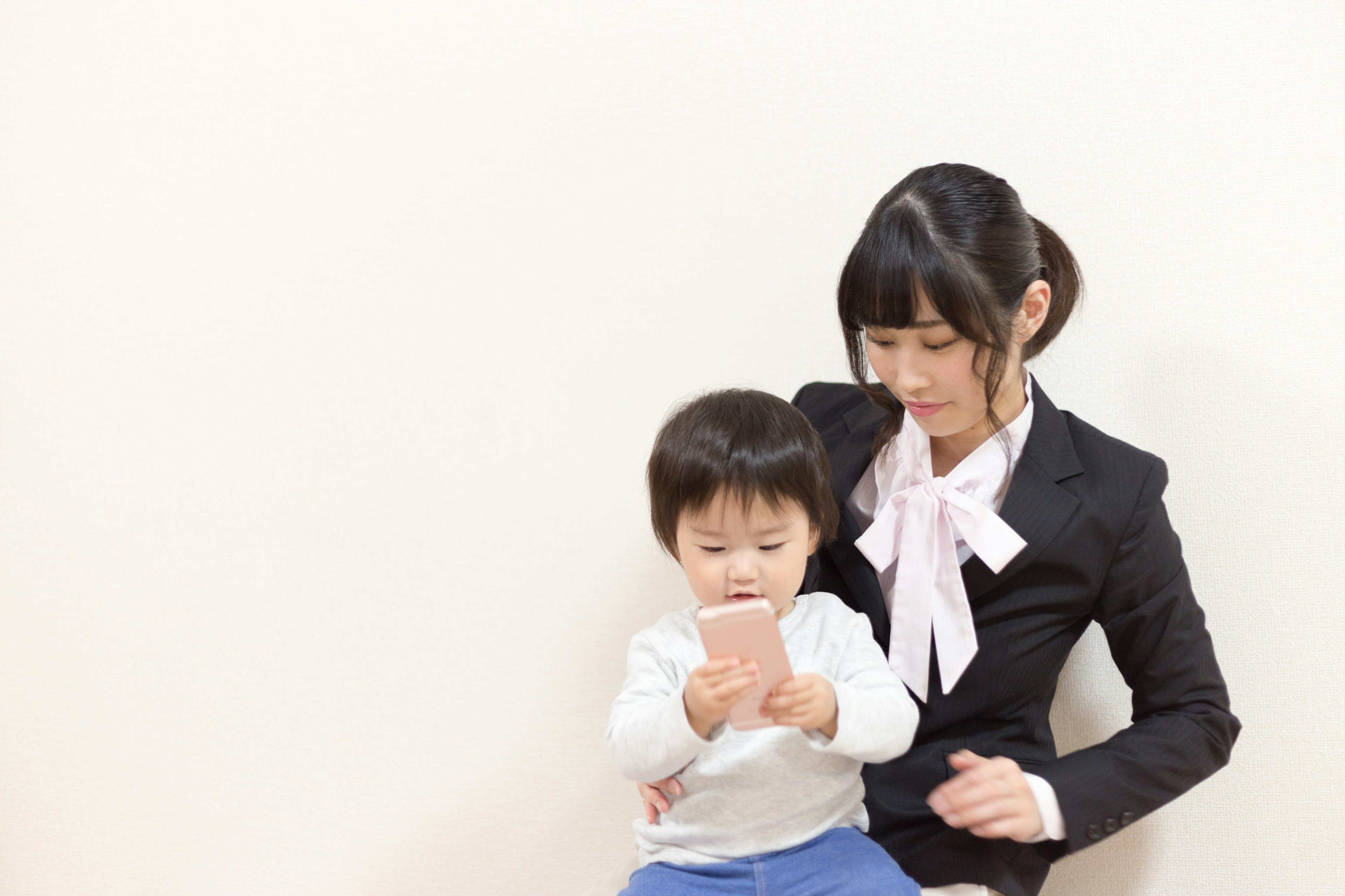 A woman in a suit sitting with a child holding a smartphone