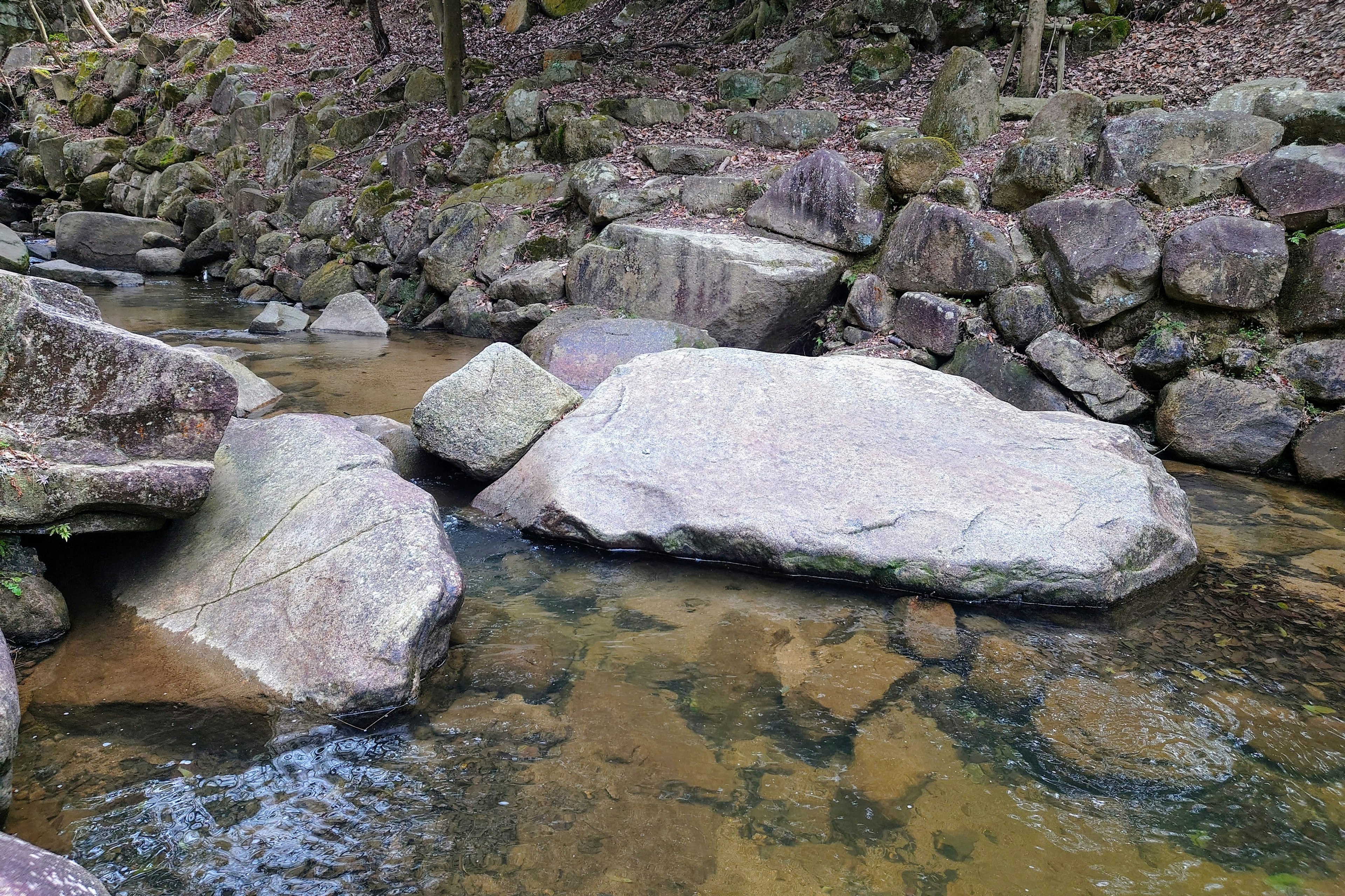 Grandes rocas en un arroyo con un muro de piedra