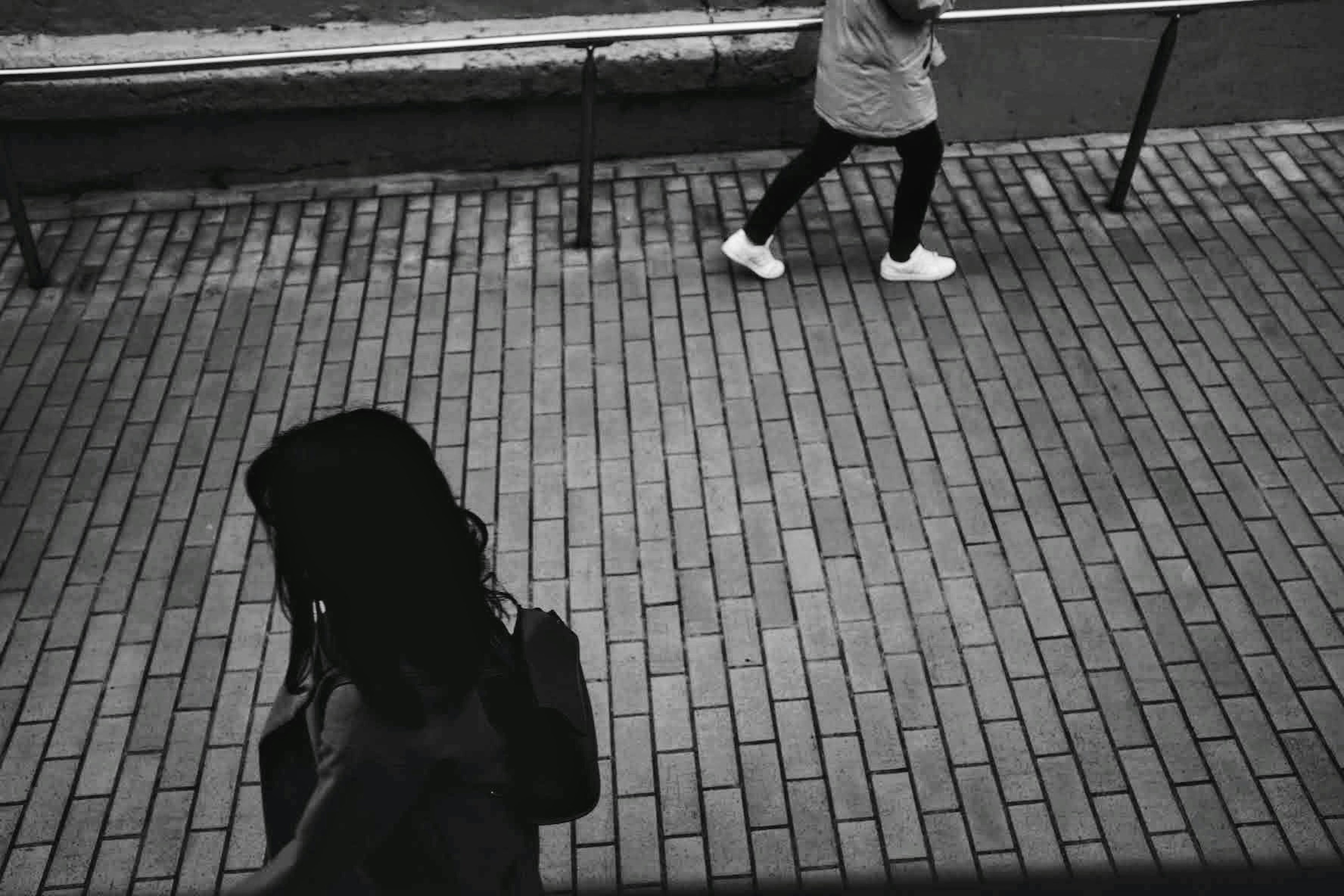 Une femme marchant dans une scène urbaine avec une autre personne qui passe