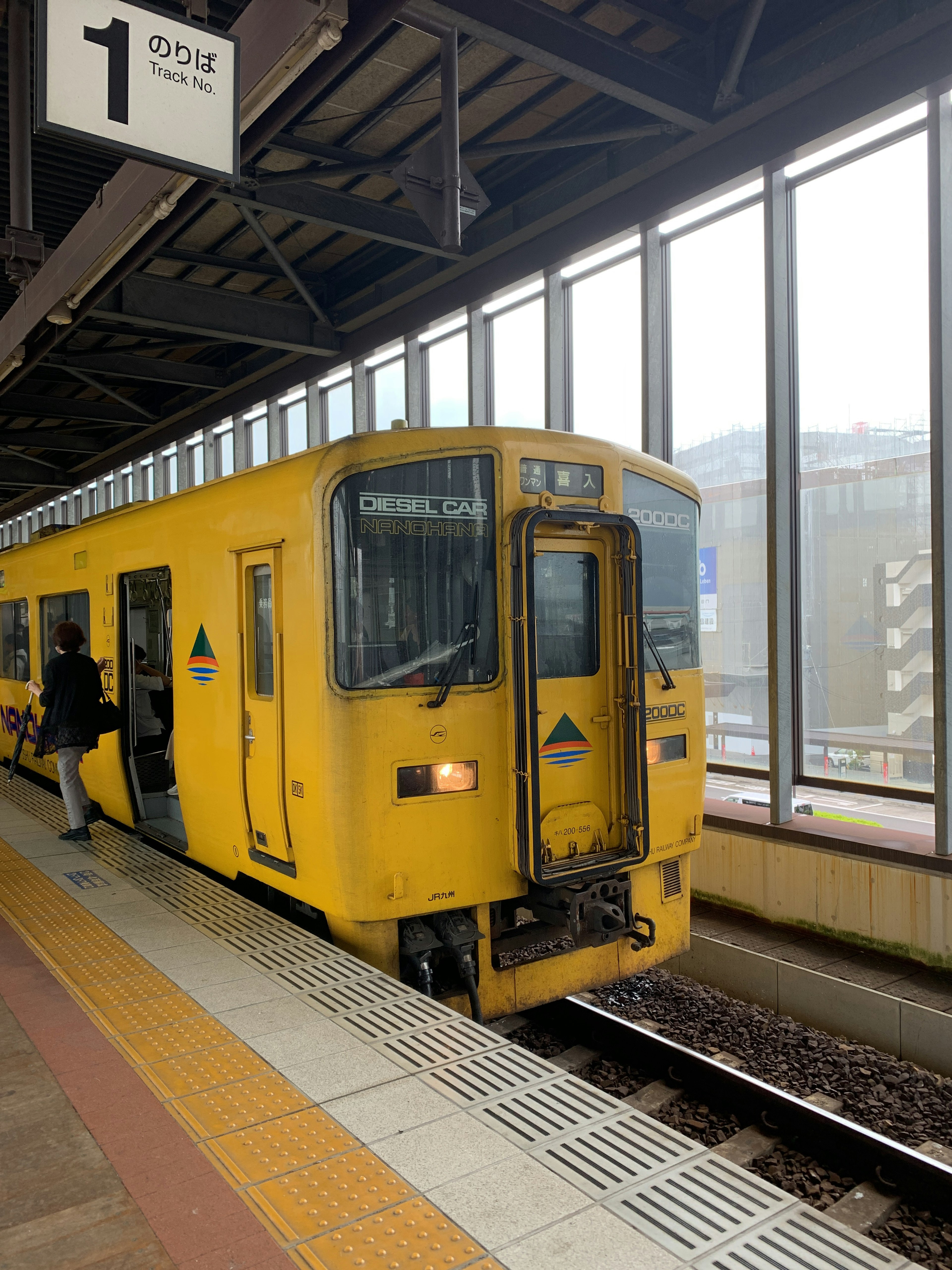 一列黃色火車在車站停靠，乘客上車