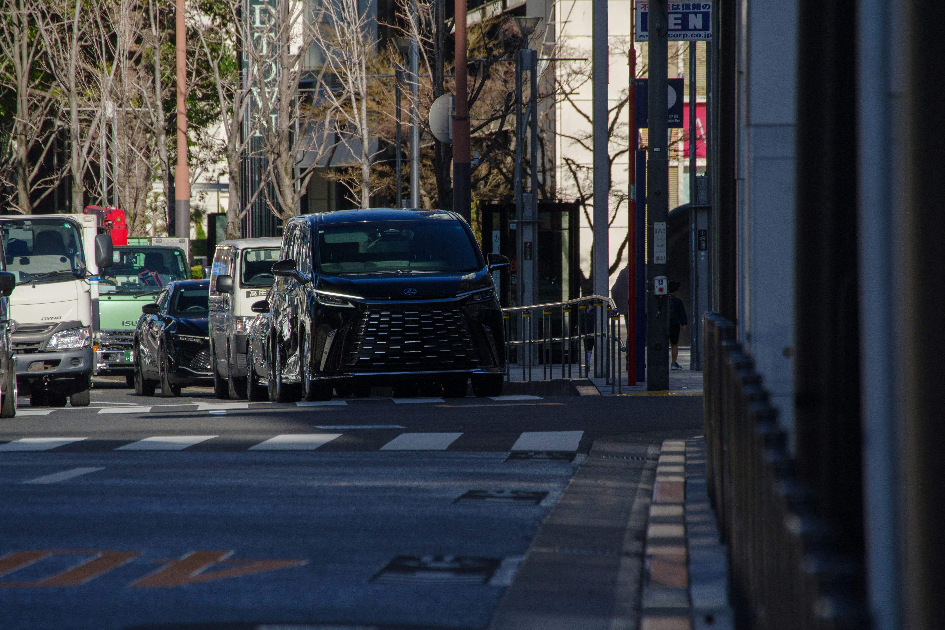 街の交差点に停車している黒い車と周囲の風景