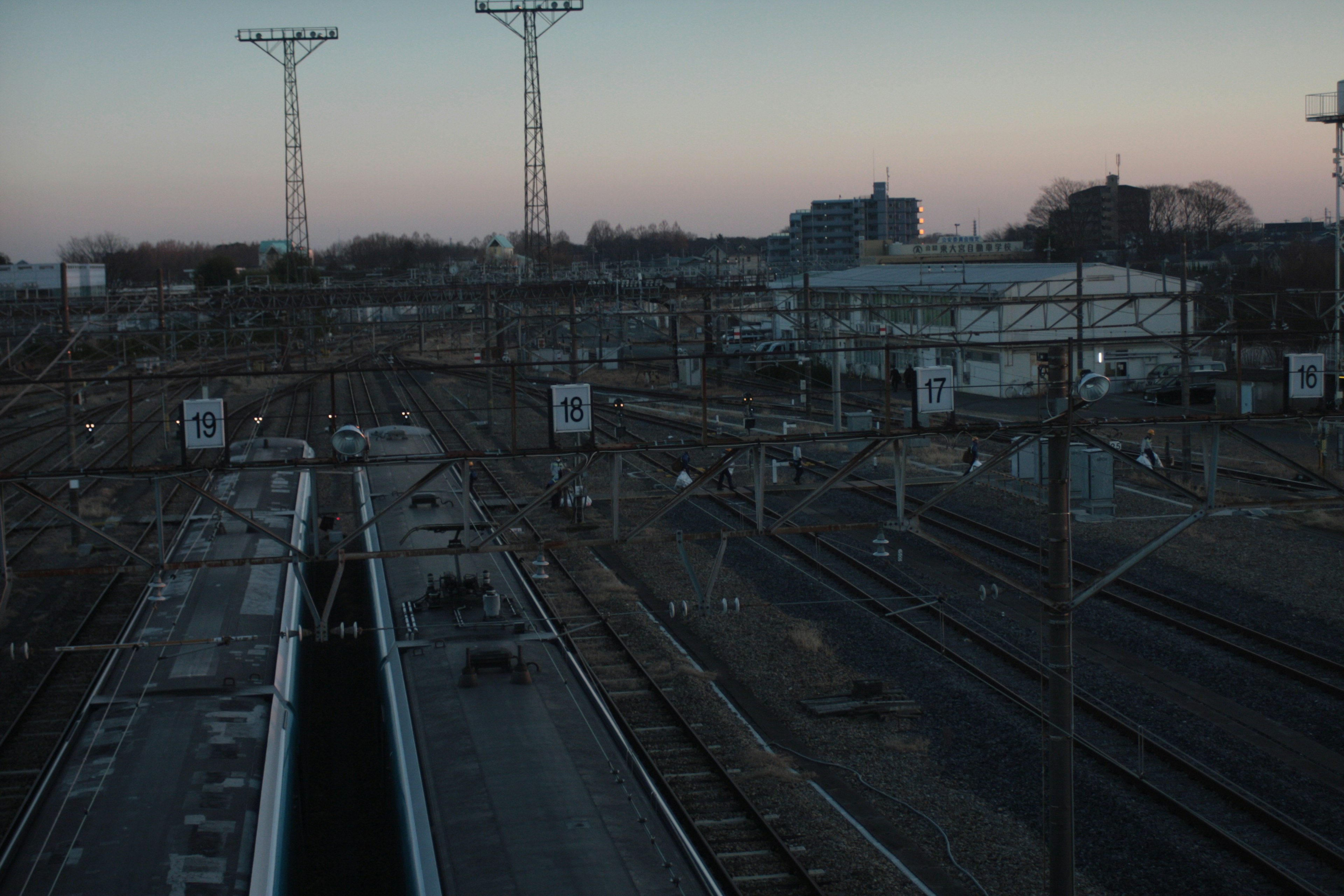 Scène ferroviaire au crépuscule avec plusieurs voies et poteaux électriques visibles