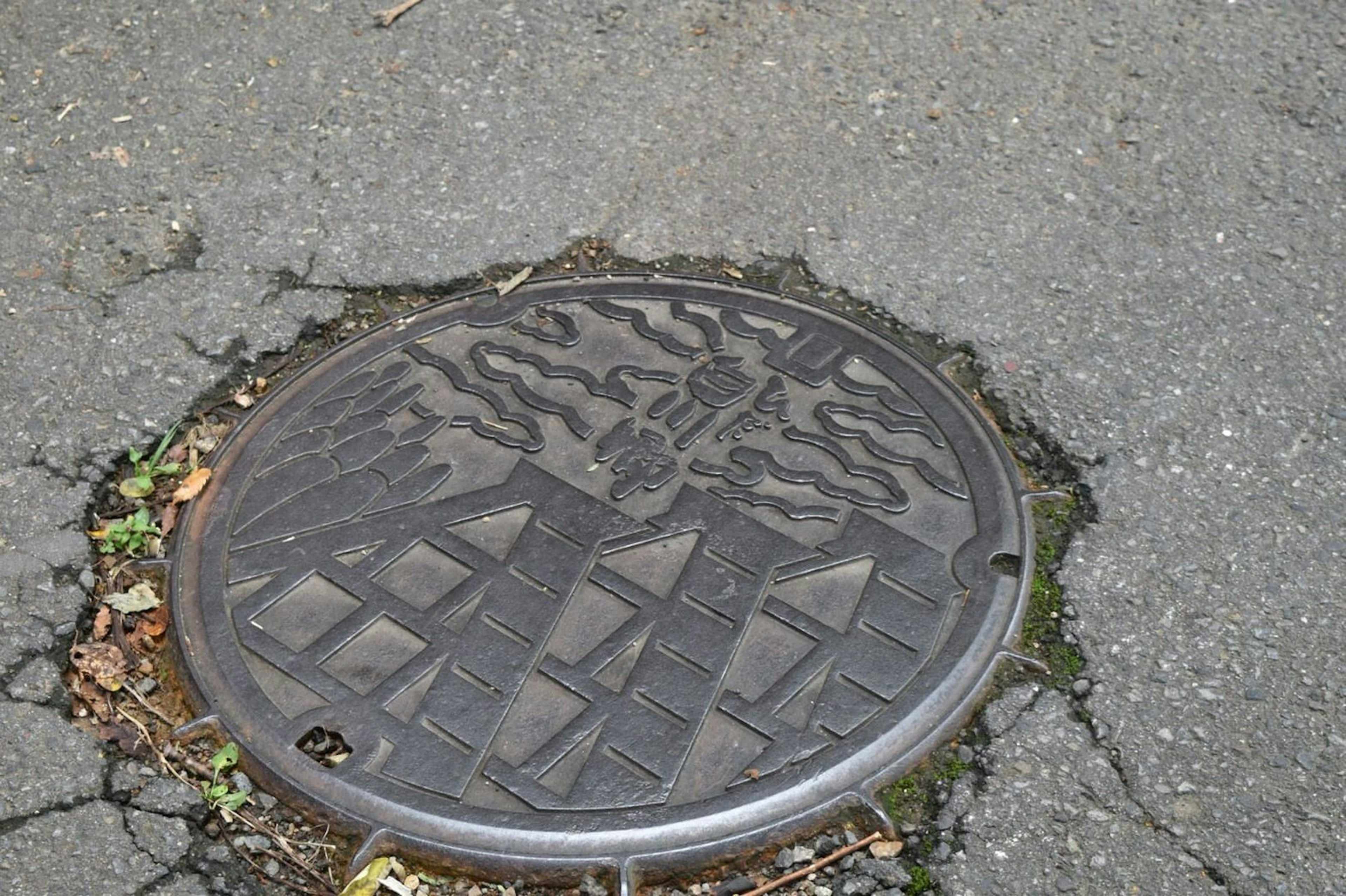 道路のマンホールカバーがひび割れたアスファルトに置かれている