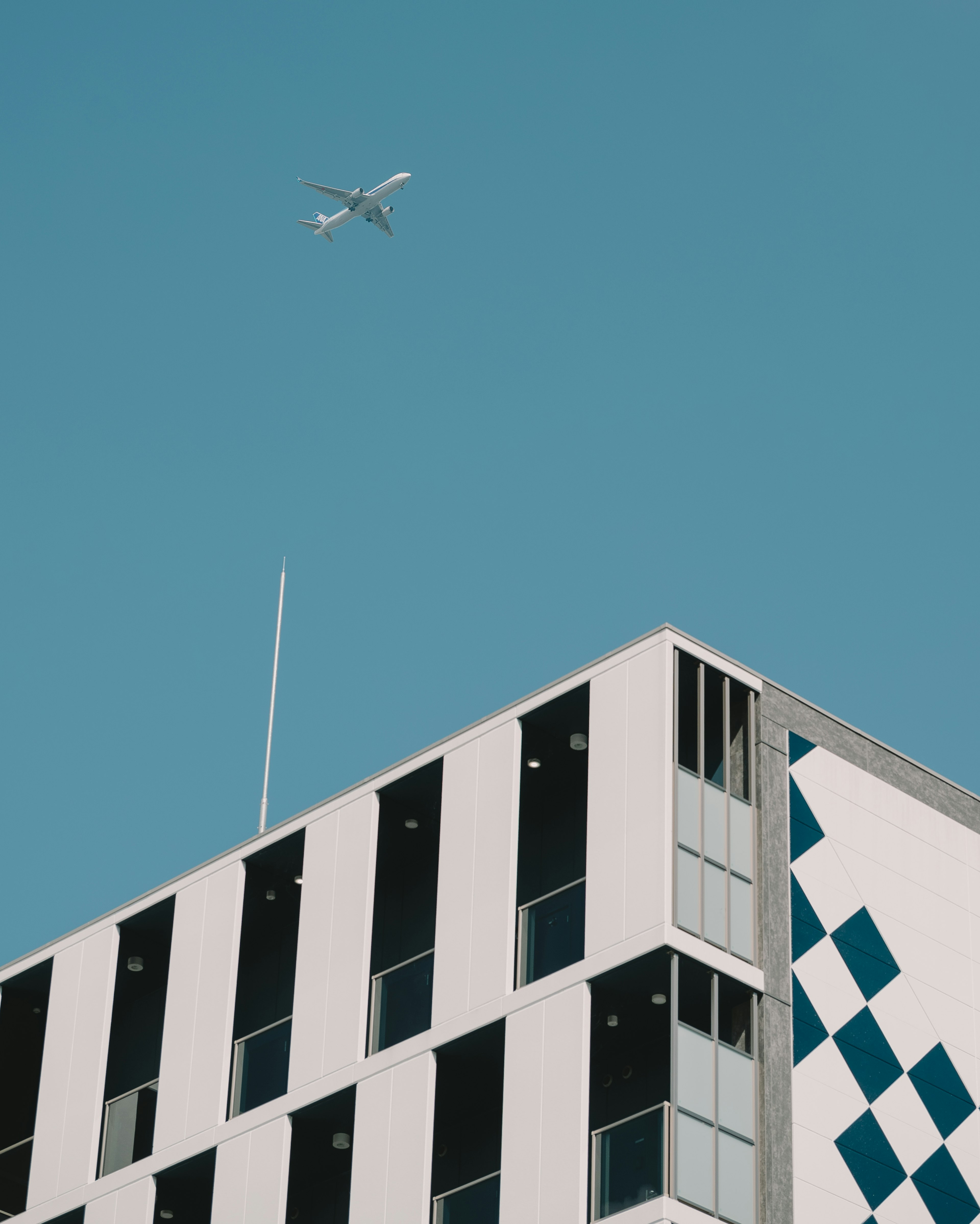 Ein modernes Gebäude mit einem Flugzeug, das in einem klaren blauen Himmel fliegt