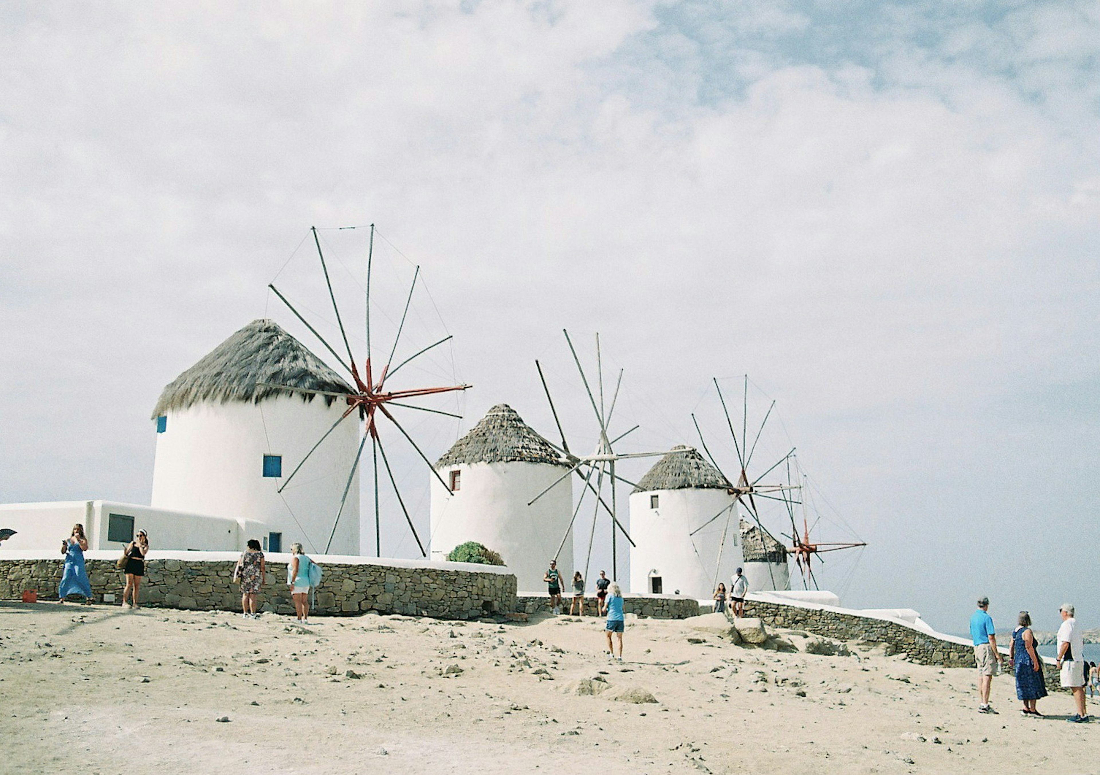 Weiße Windmühlen an einem Strand mit Touristen