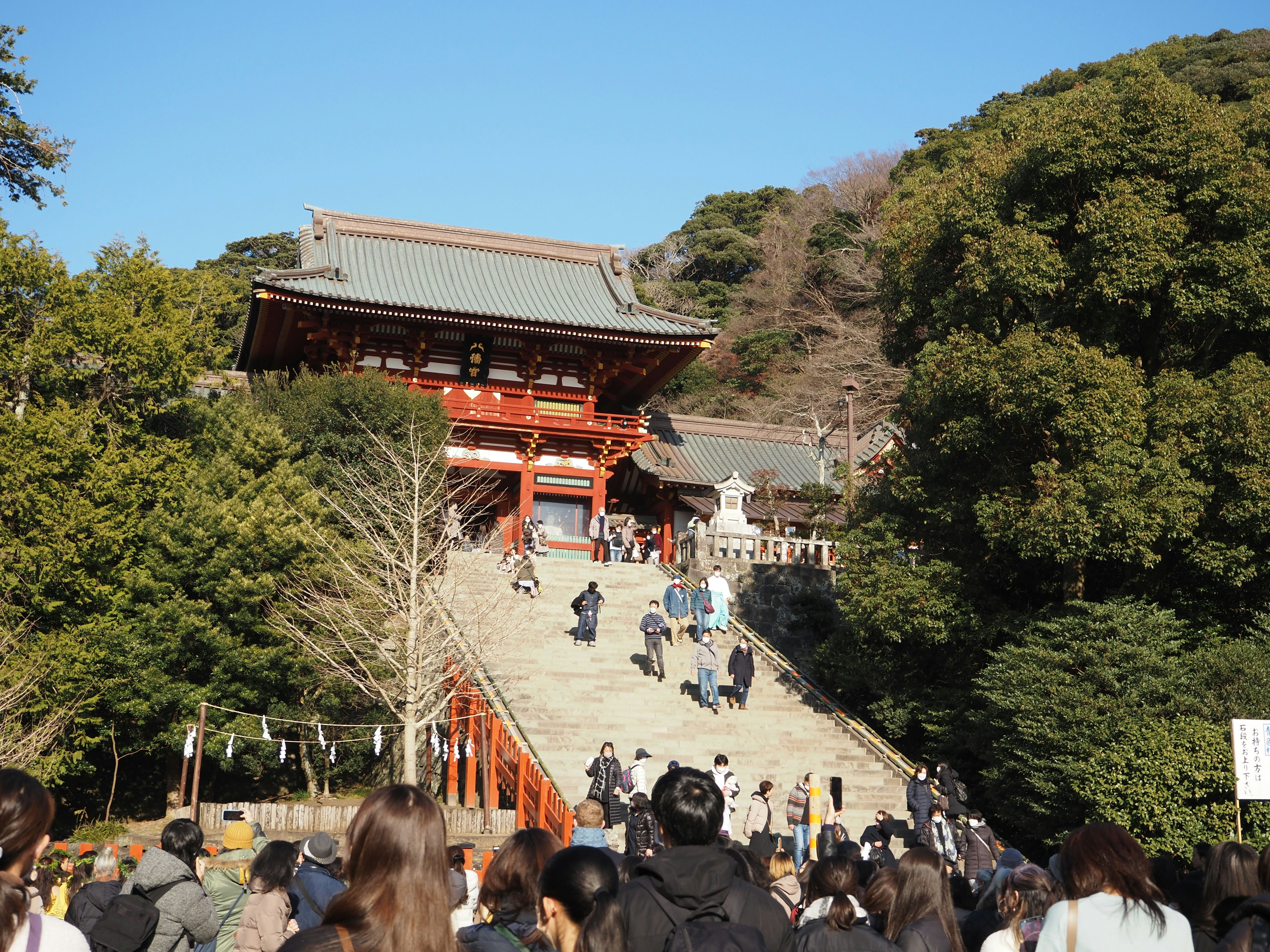 Scene of people ascending stairs at a shrine with a red gate