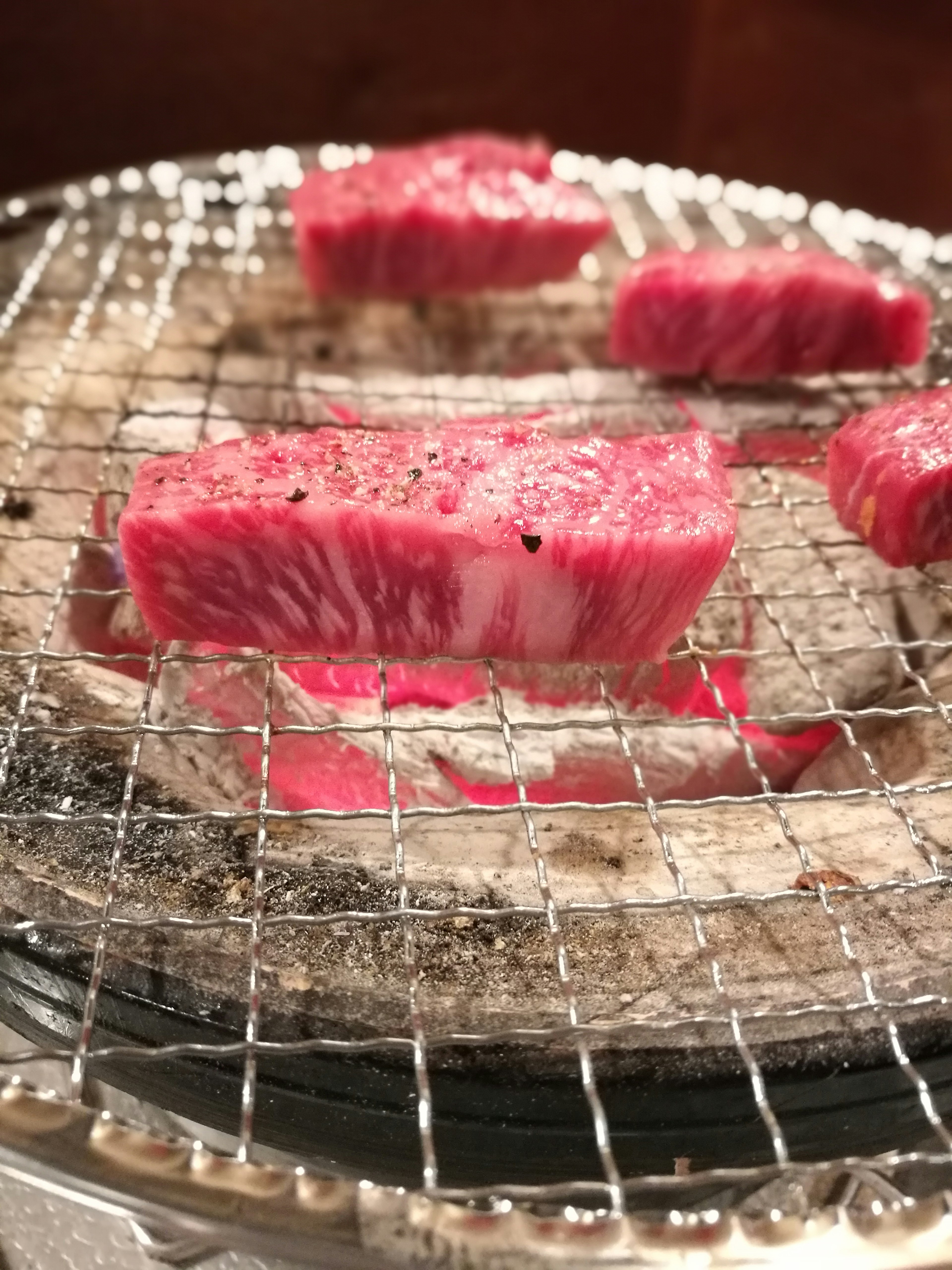 Slices of marbled beef grilling on a wire rack