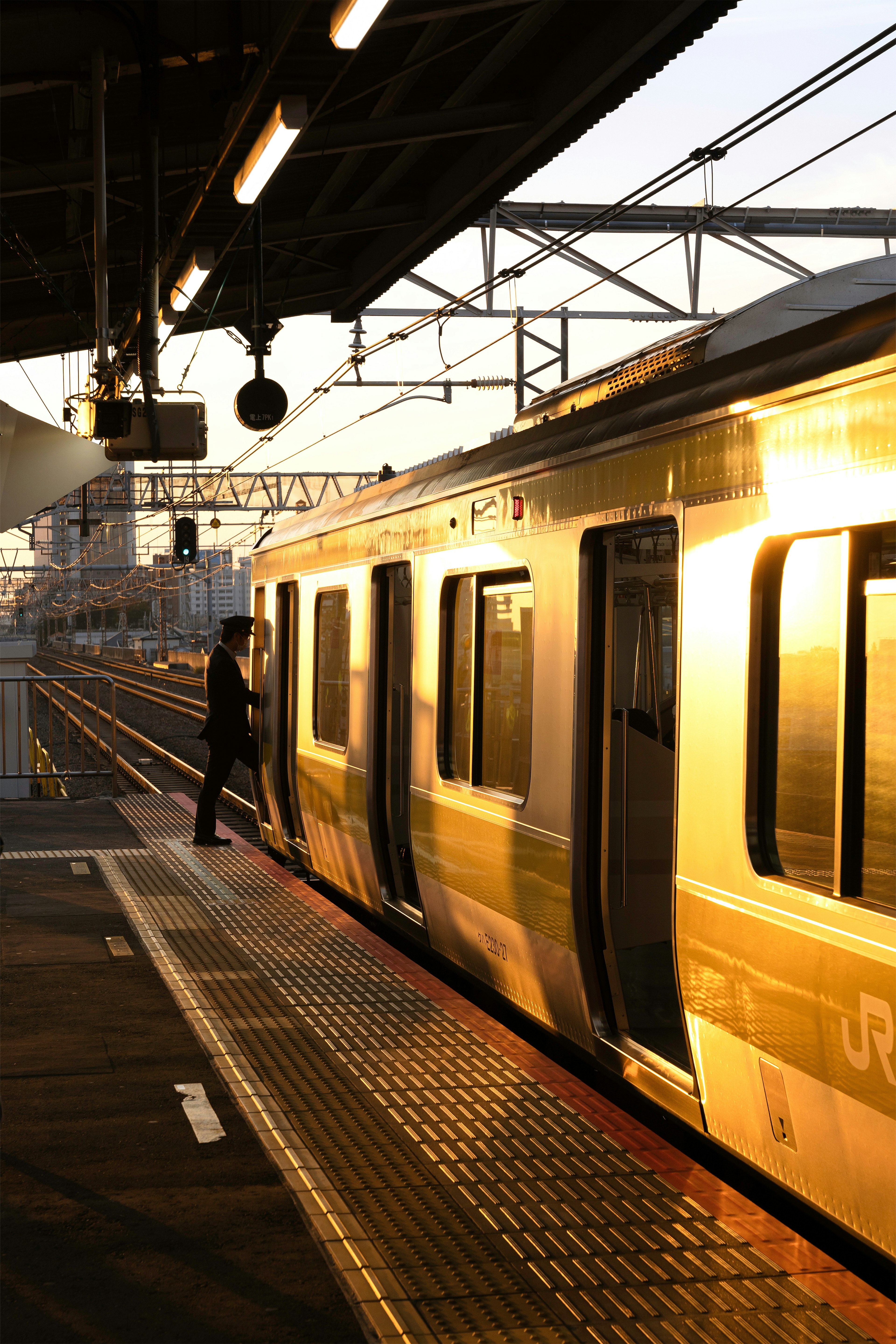 Tren en una estación durante el atardecer con un pasajero subiendo