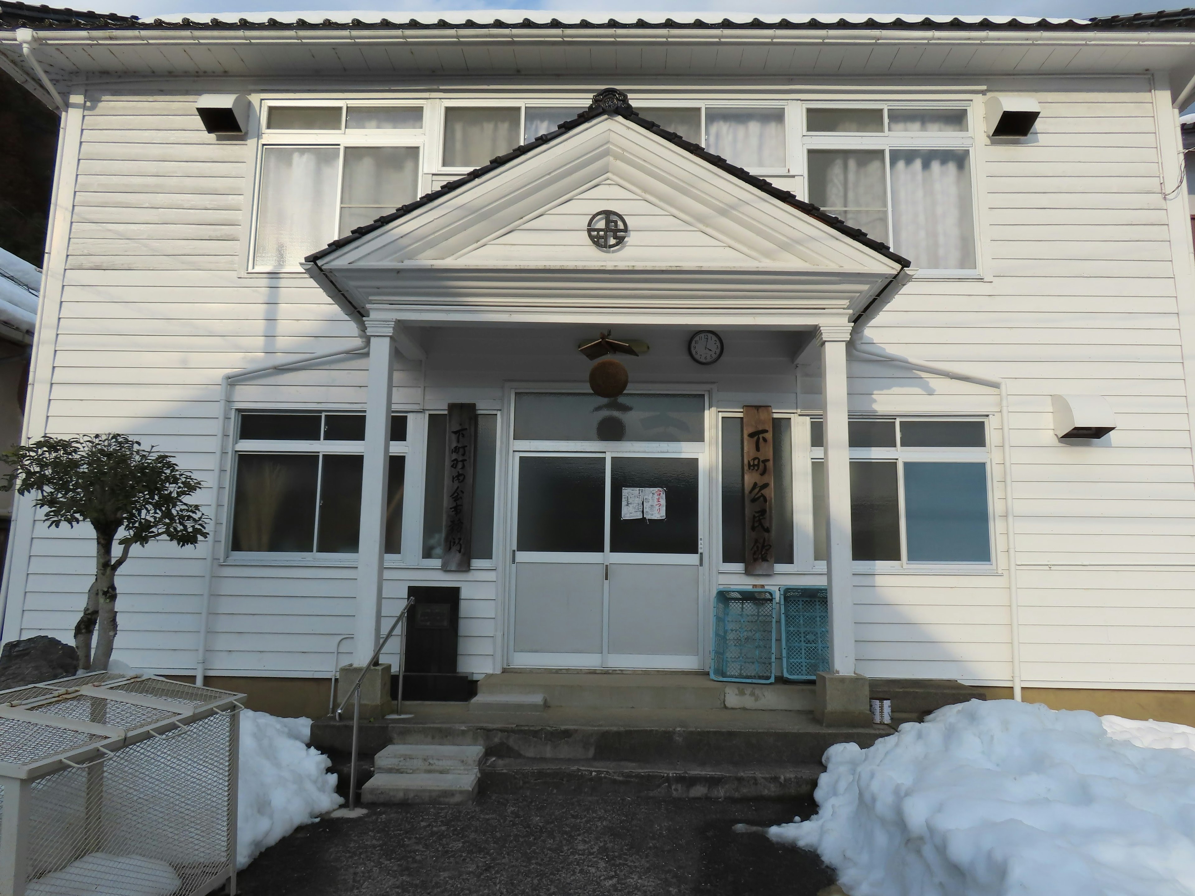 Vorderansicht eines weißen Hauses mit Schnee im Vordergrund mit Fenstern und einer Tür