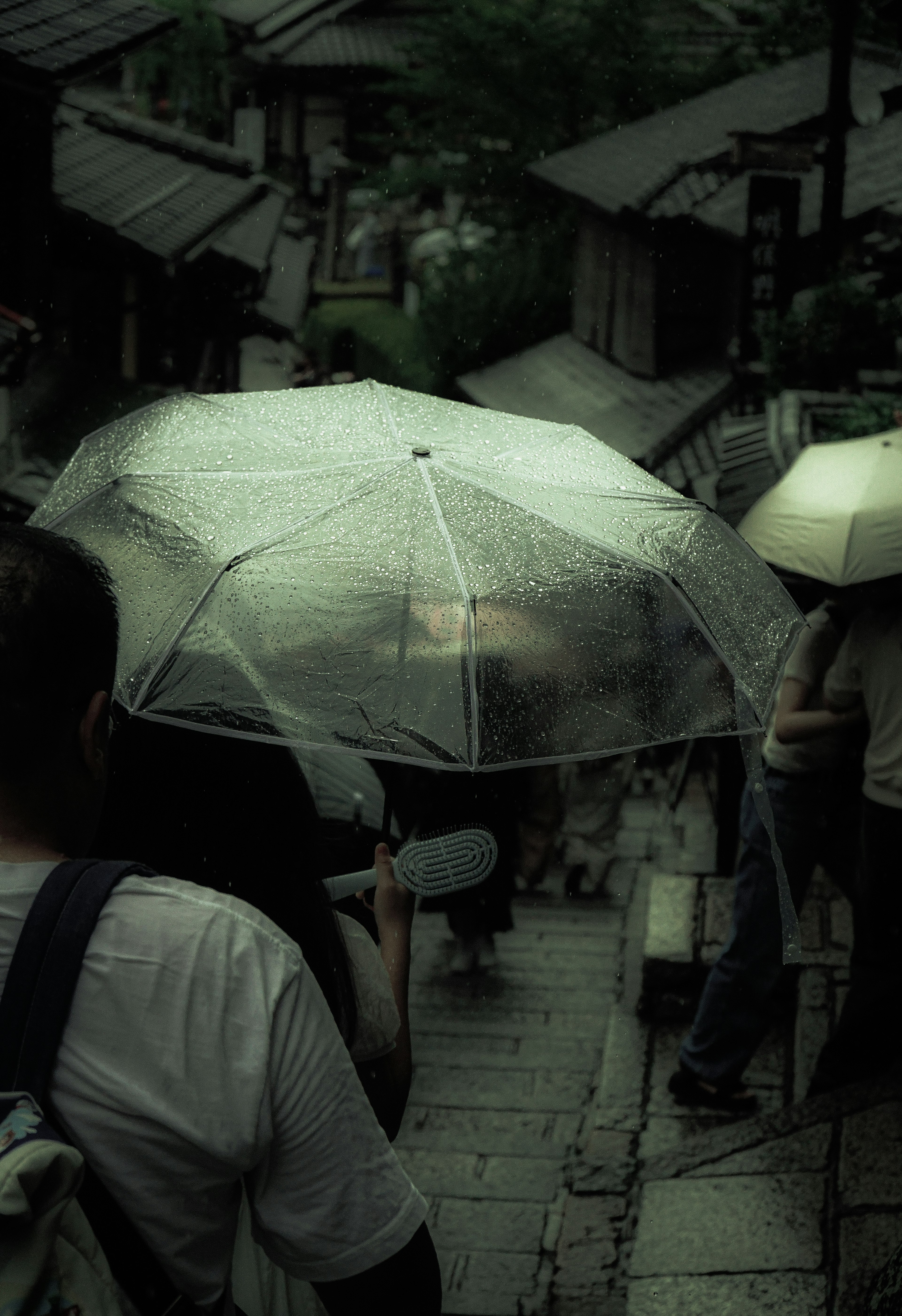 雨の中の傘を持った人々が階段を下りている風景