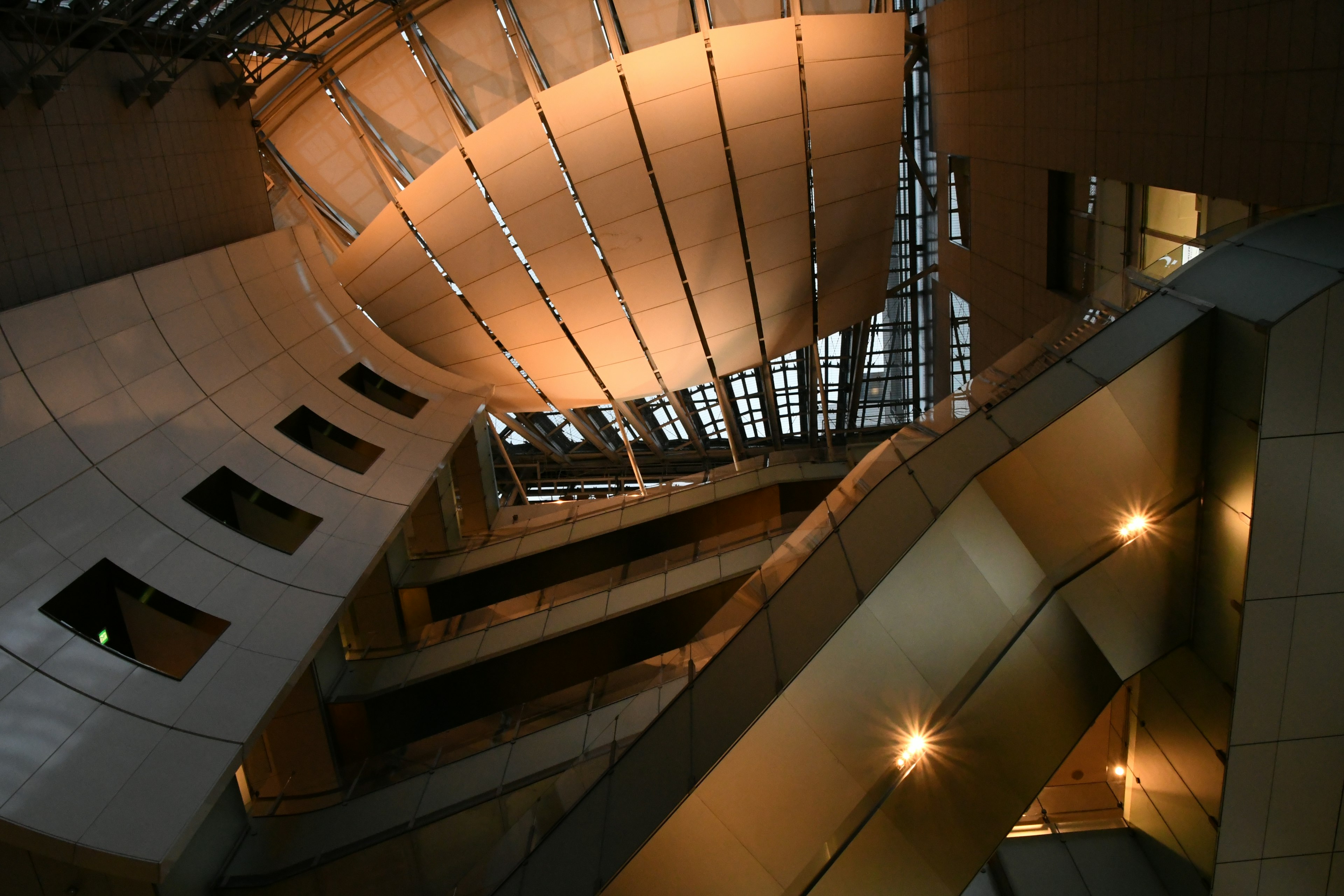 Vista interior de una estructura arquitectónica moderna desde arriba con una mezcla de curvas y líneas con luz natural que entra