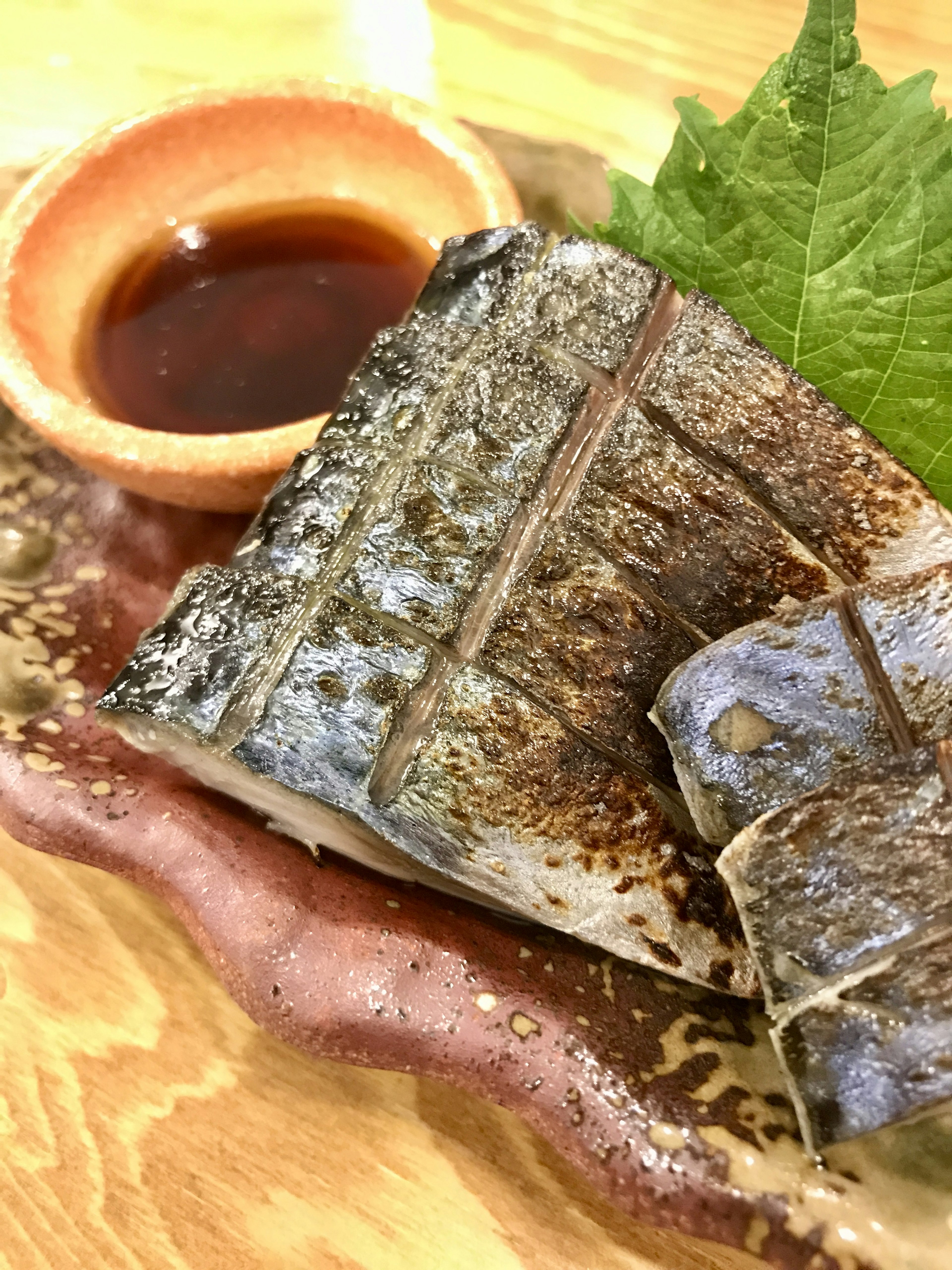 Filetto di pesce grigliato servito con salsa di soia e foglia di shiso fresco